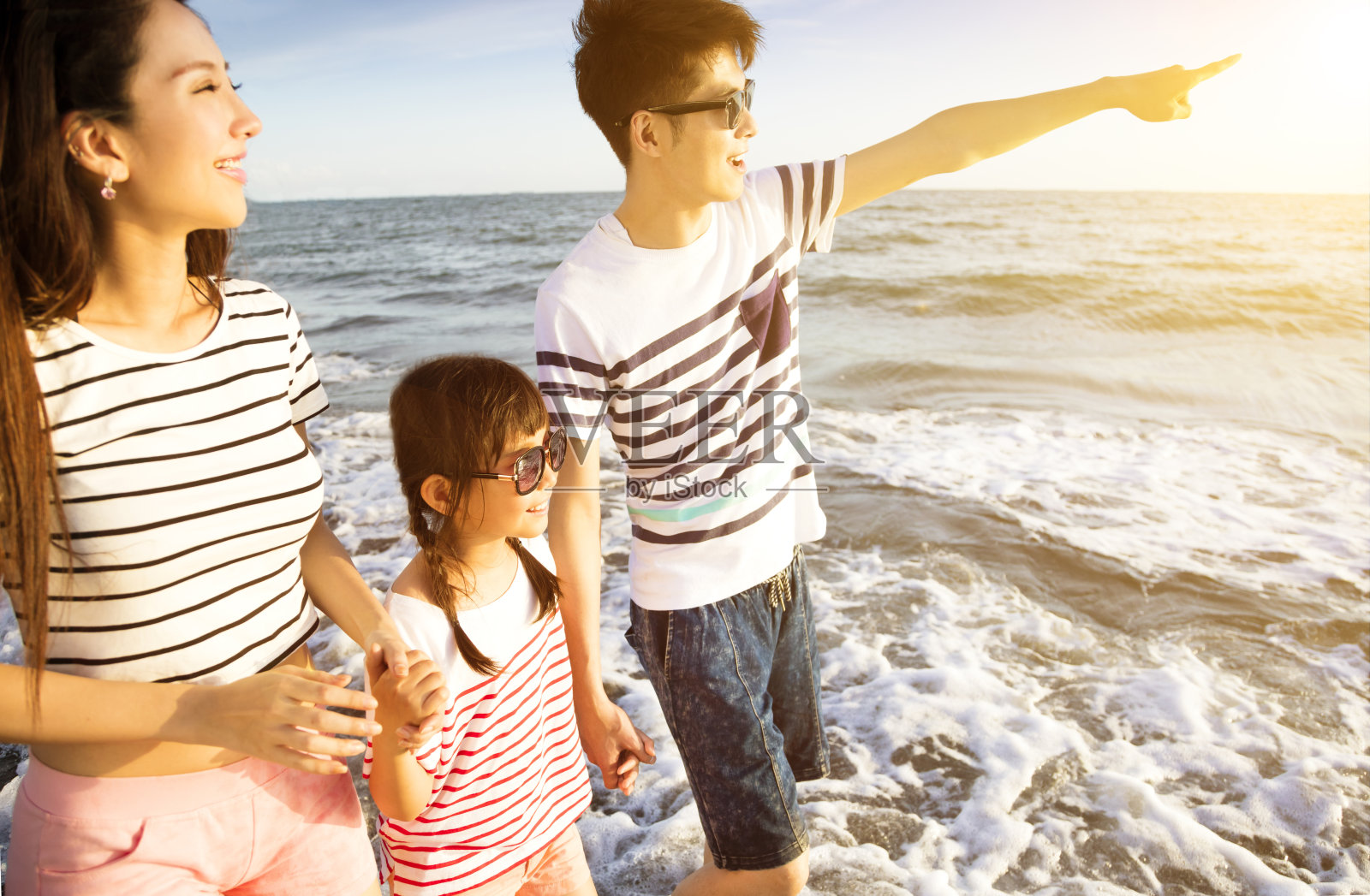 快乐的一家人在暑假的海滩上散步照片摄影图片