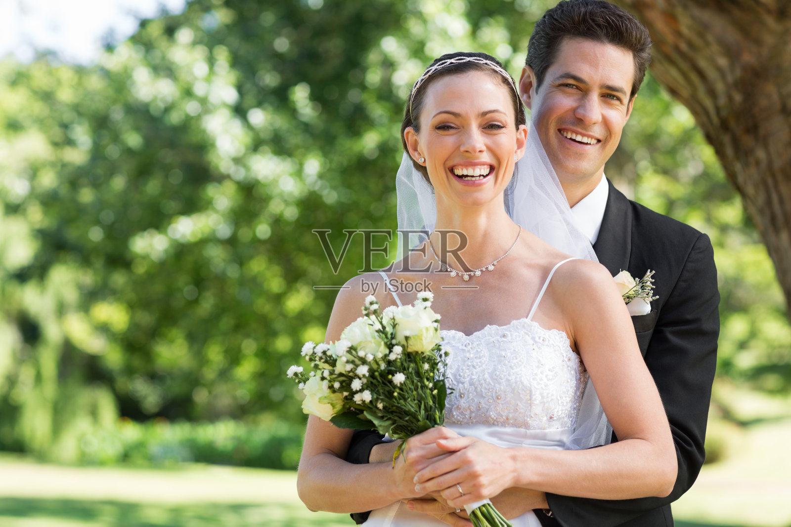 新婚夫妇手持花束在公园里照片摄影图片