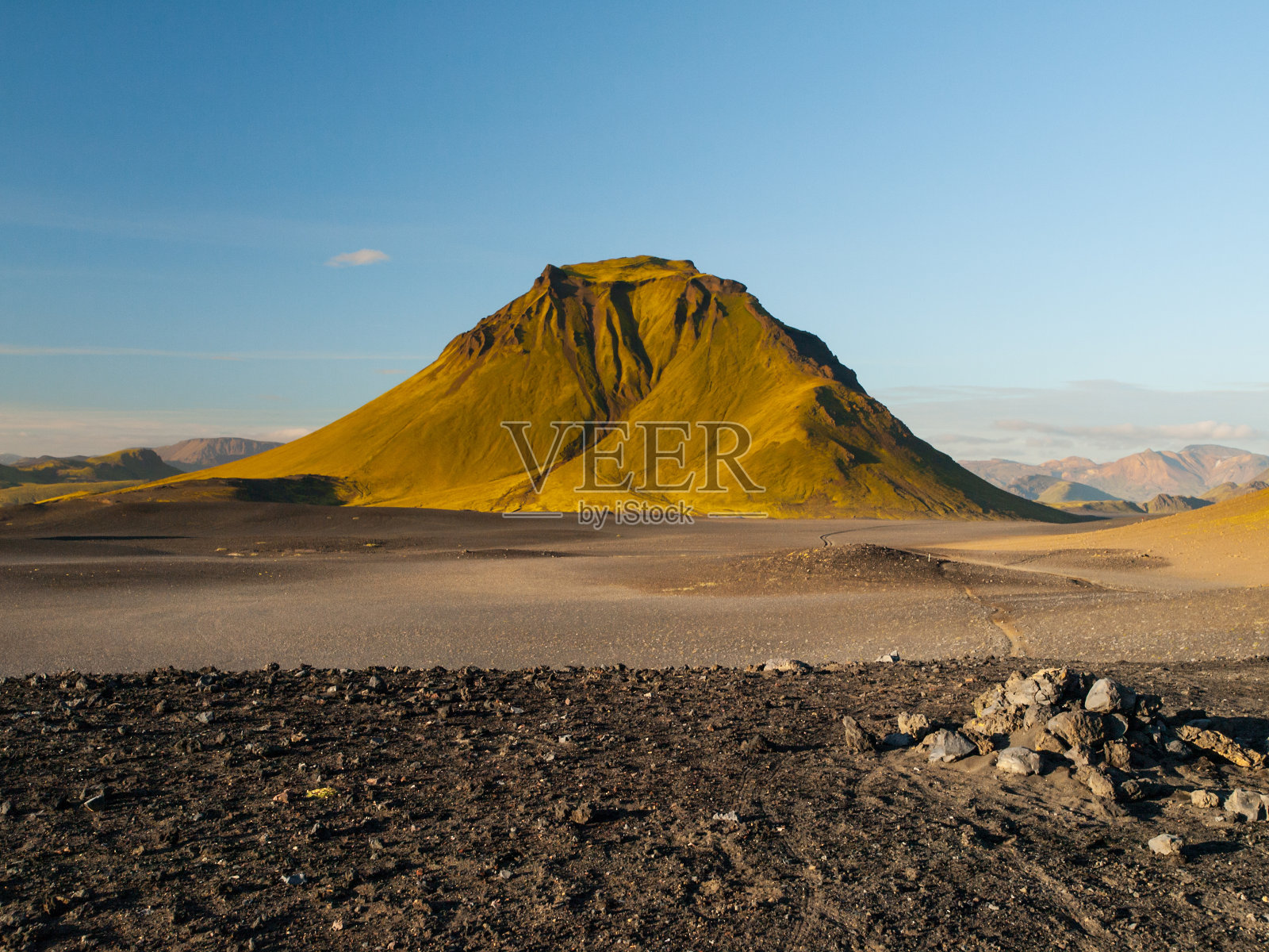 冰岛拉格维古尔徒步旅行路线沿途的冰岛高地上的绿色山丘和黑色岩石地面。阳光明媚的夏日拍摄照片摄影图片