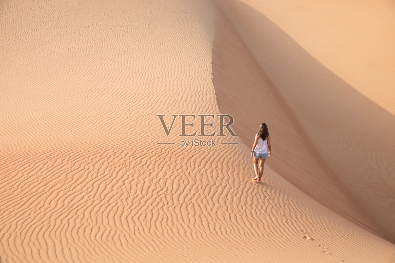 美丽的女人在巨大的沙丘上徒步旅行。照片摄影图片