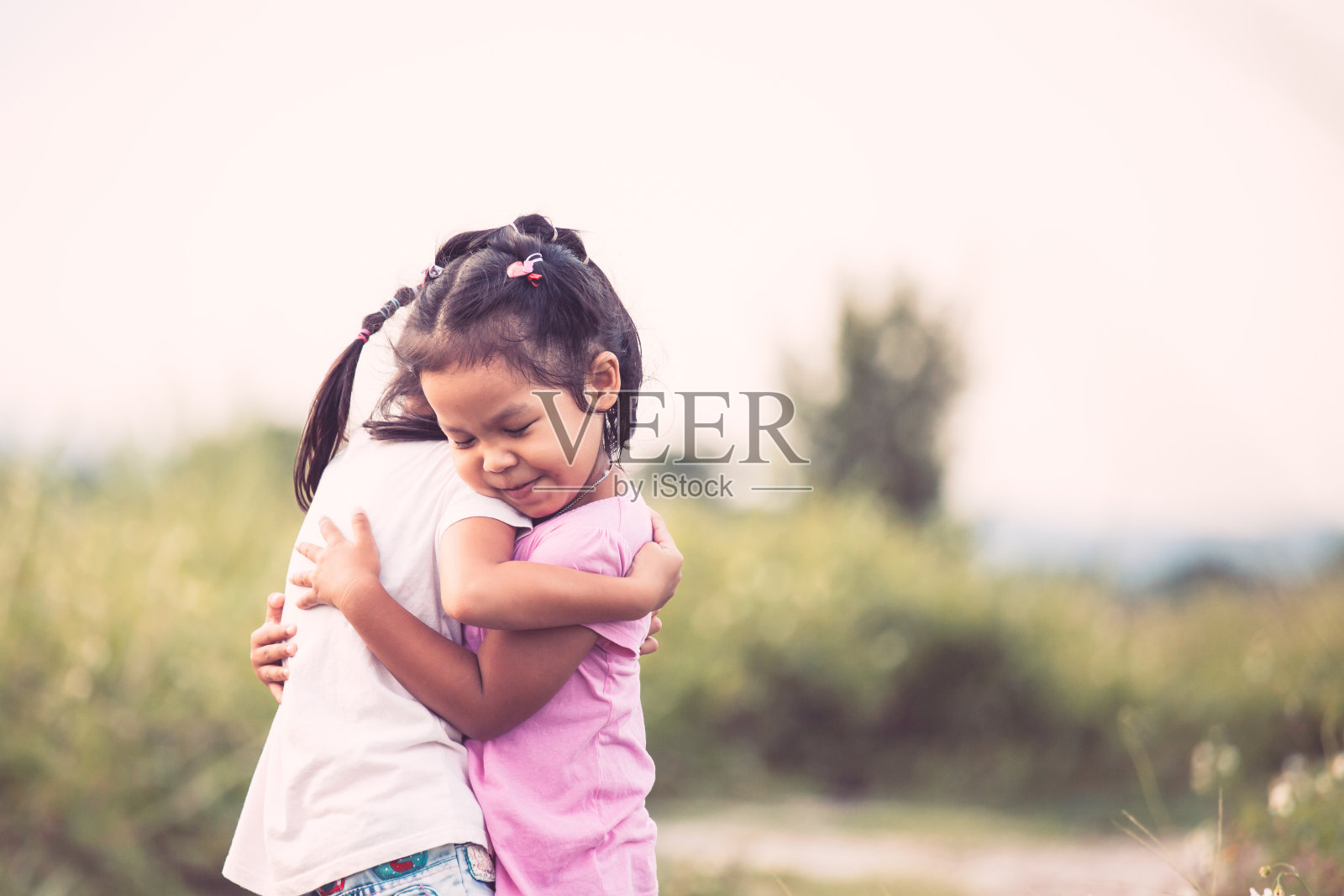 两个亚洲小女孩充满爱意地拥抱在一起照片摄影图片