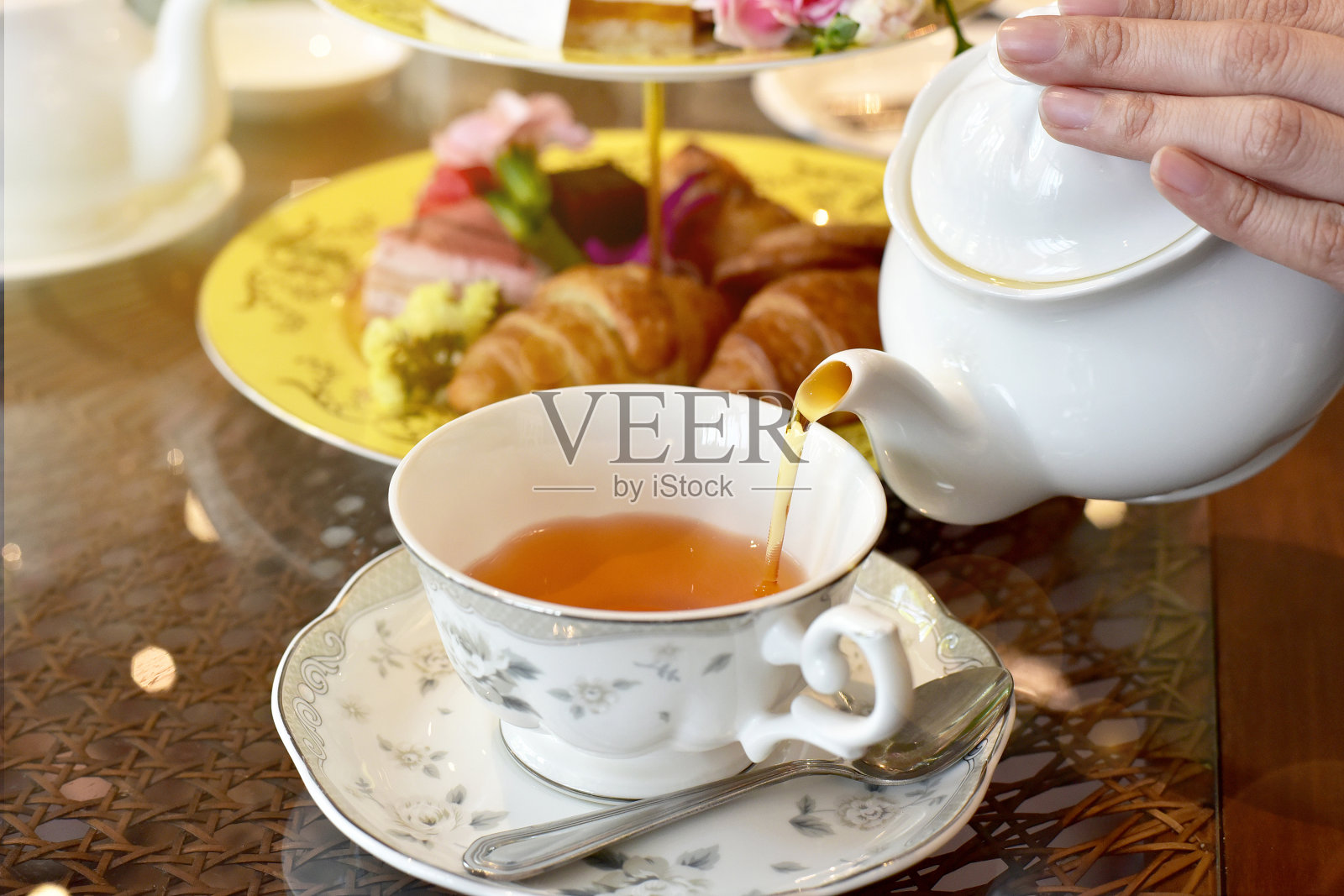 从老茶壶倒茶到茶杯，英国茶时间。照片摄影图片