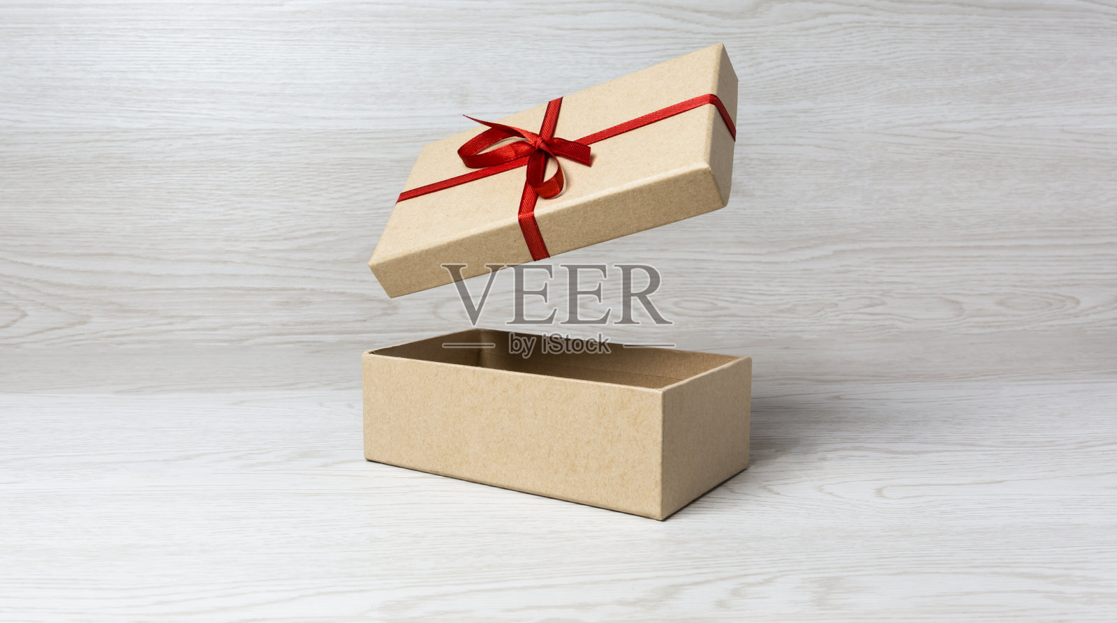 素色礼盒，封面用白色木质背景上的红色蝴蝶结照片摄影图片