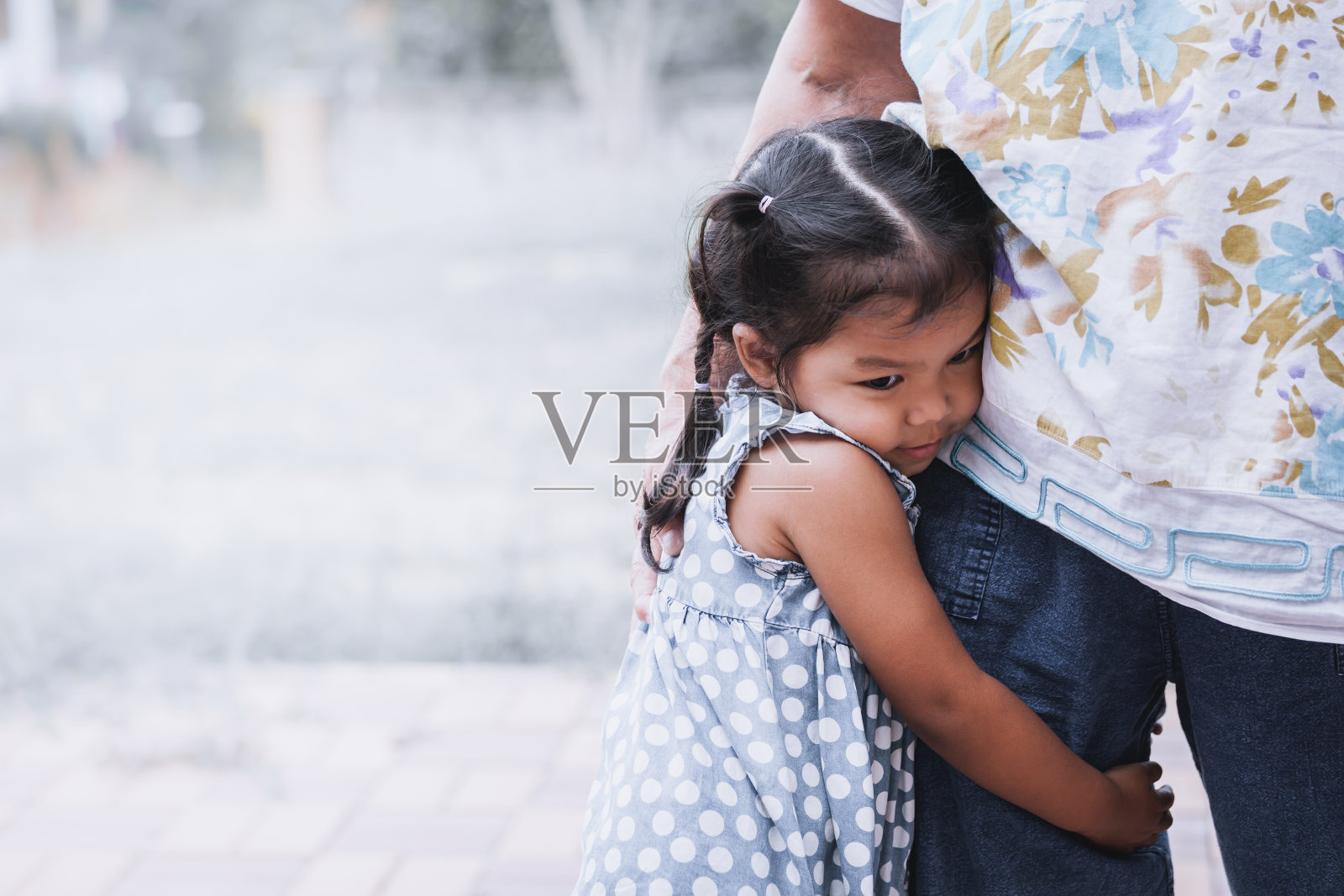 悲伤的亚洲小女孩抱着她妈妈的腿照片摄影图片