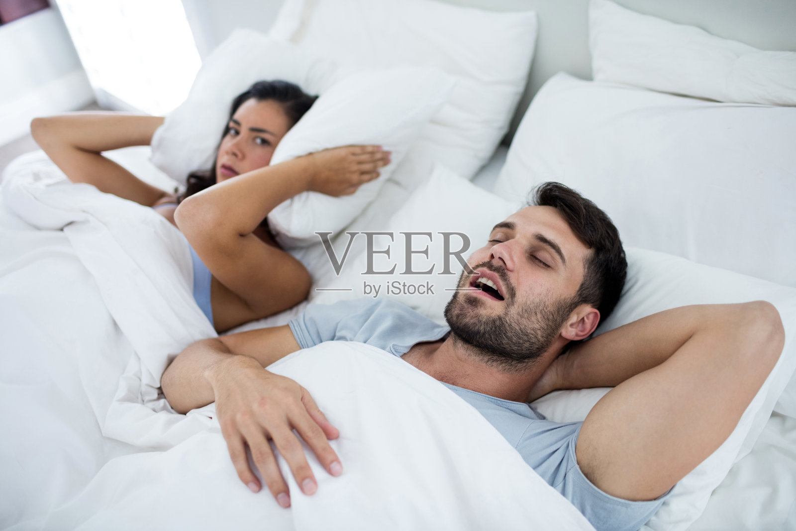 男人在床上打鼾，女人被吵醒照片摄影图片