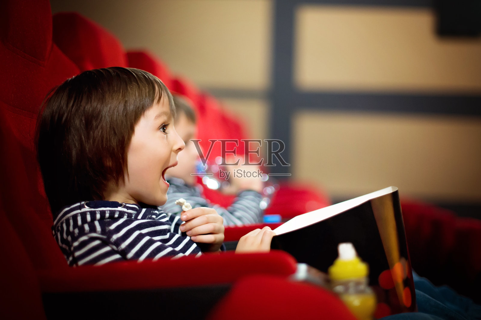 两个学龄前的孩子，双胞胎兄弟，在电影院看电影，吃爆米花照片摄影图片