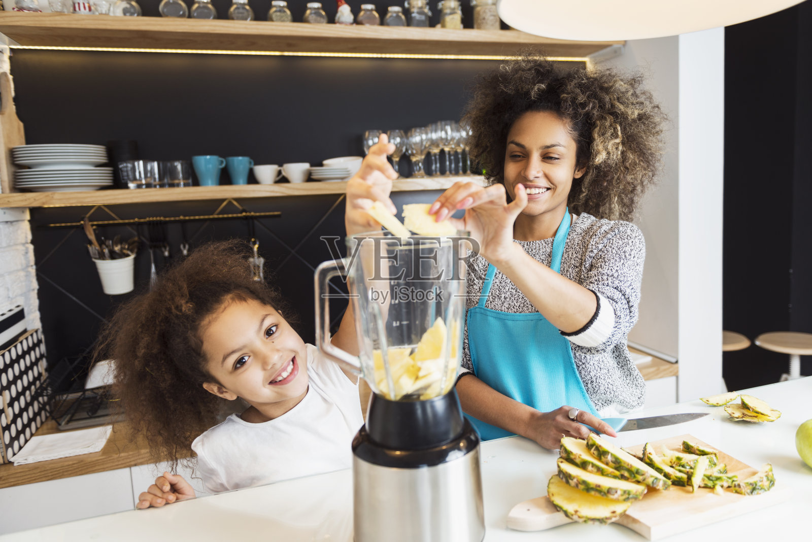 美丽的非洲裔美国妇女和她的女儿在厨房切水果照片摄影图片