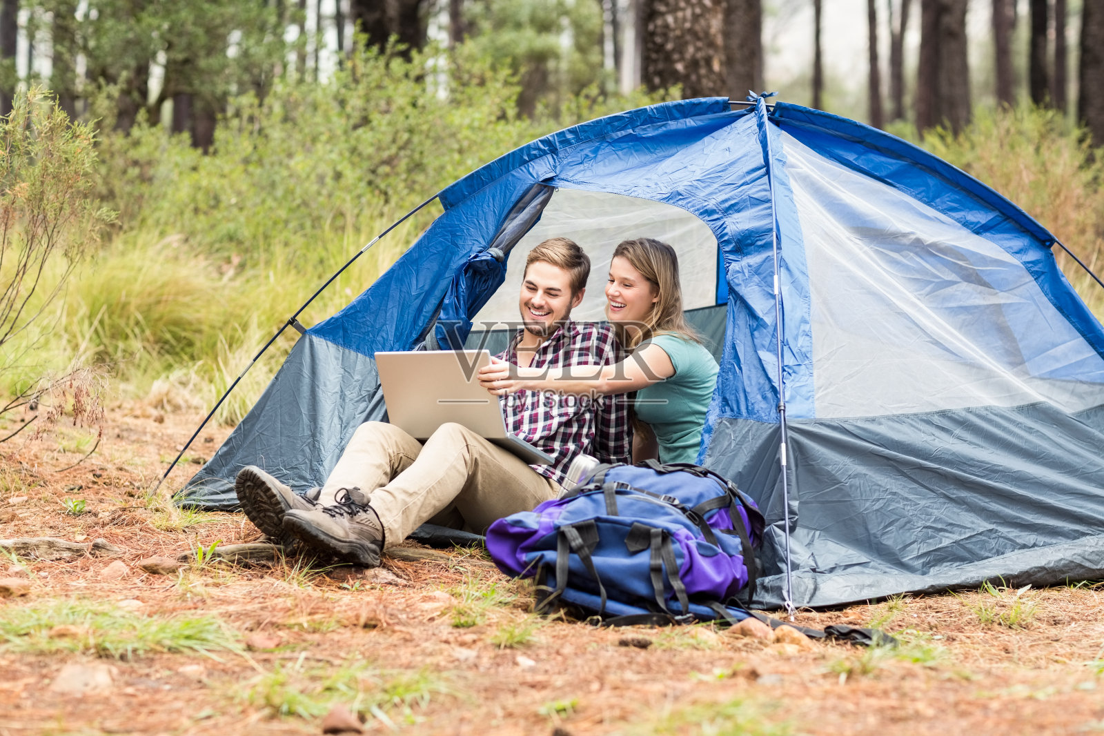 年轻漂亮的徒步夫妇坐在帐篷里看笔记本电脑照片摄影图片