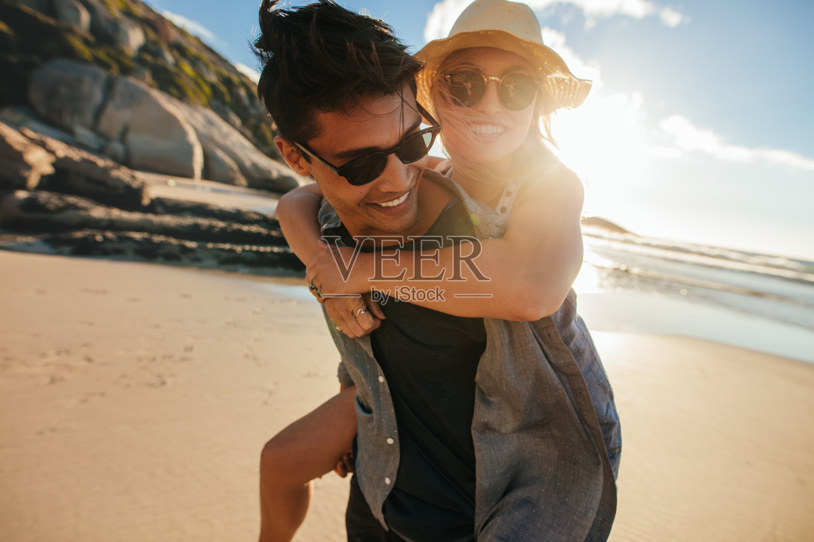 在海滩上，男朋友背着他的女朋友照片摄影图片