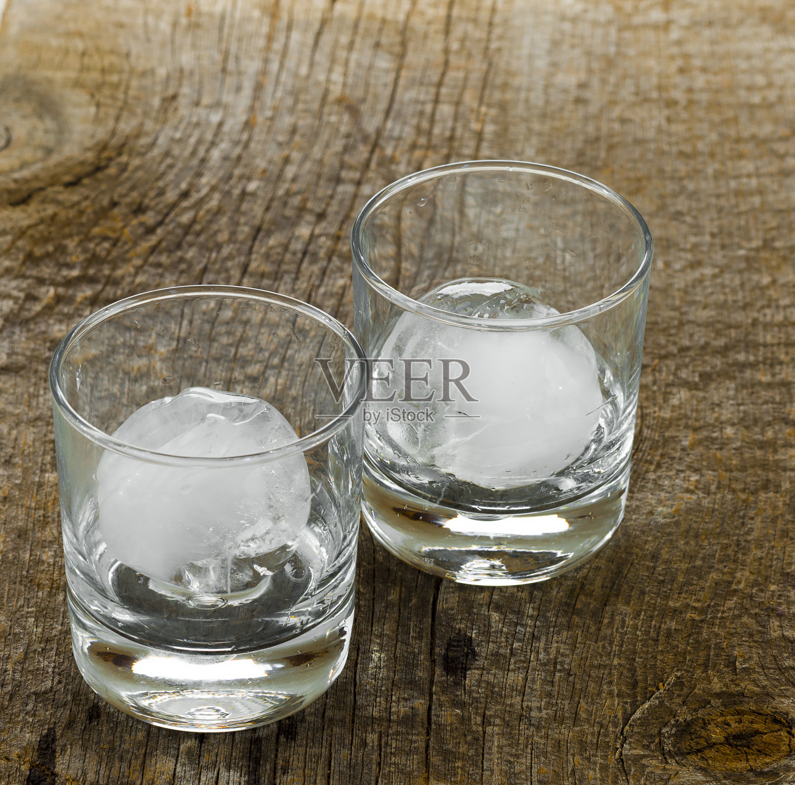 酒杯放置在质朴的谷仓木背景上，里面有圆形的冰块。照片摄影图片