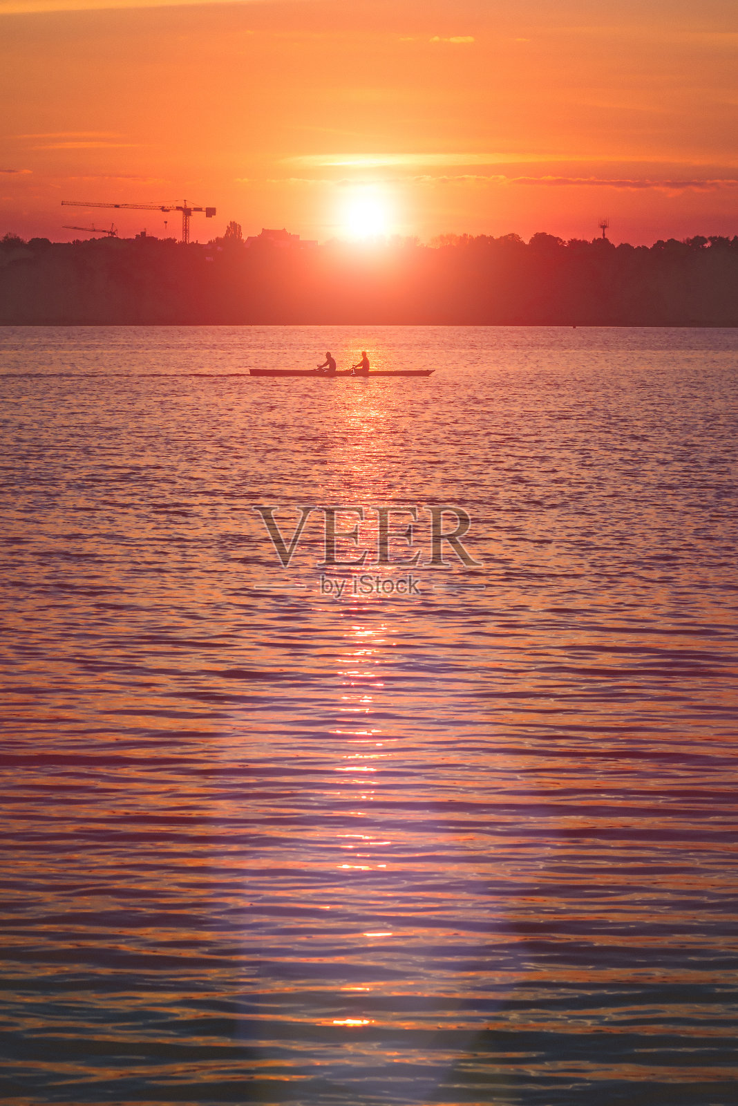 日落时分，两个年轻人划着小船照片摄影图片