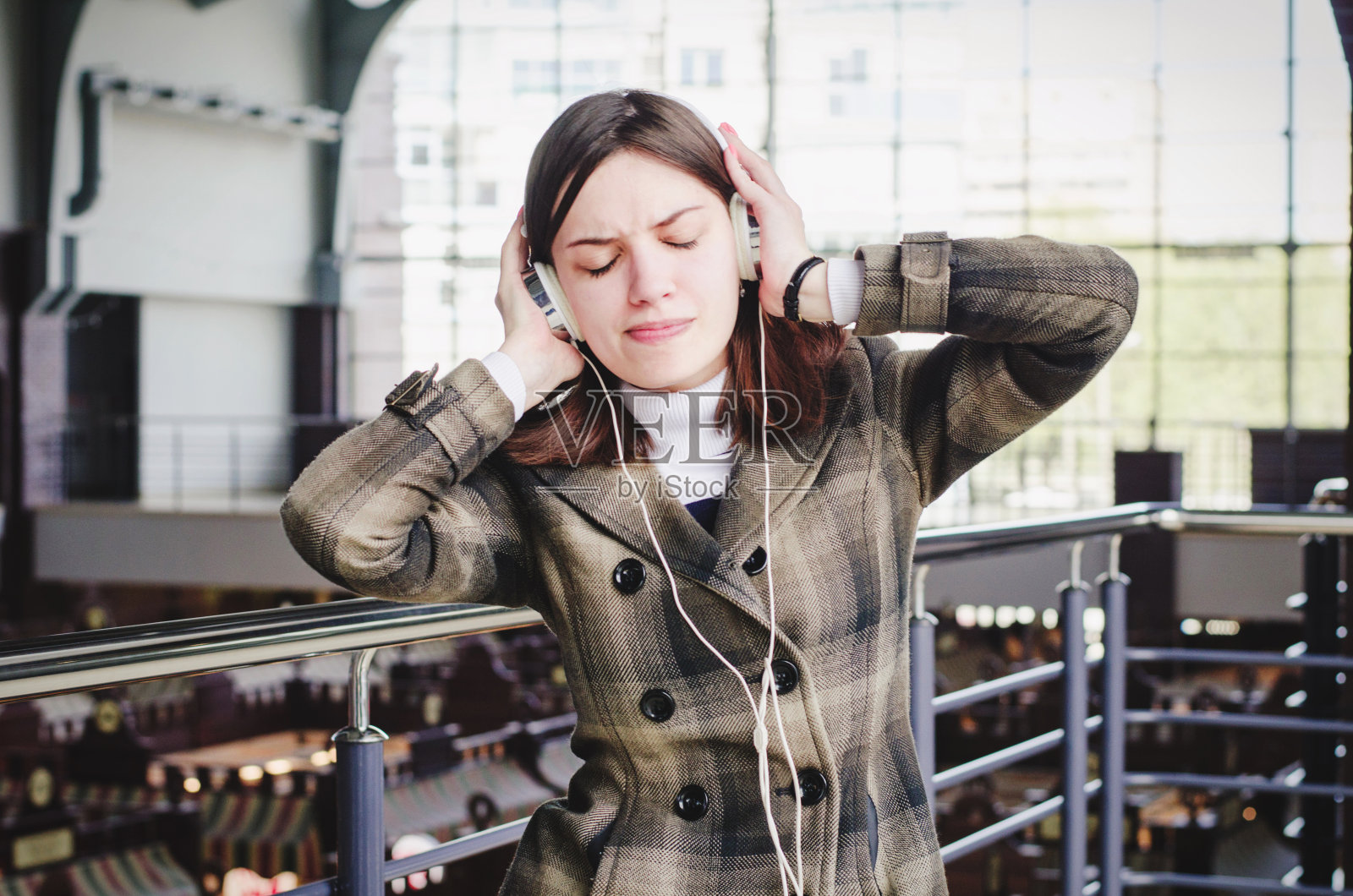 开朗快乐的黑发苗条女孩在一个购物中心有乐趣听音乐耳机照片摄影图片