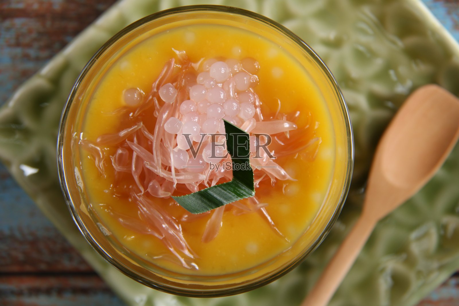 冰芒果蜜柚甜点在老式玻璃和木勺，在花压花的方形盘子照片摄影图片