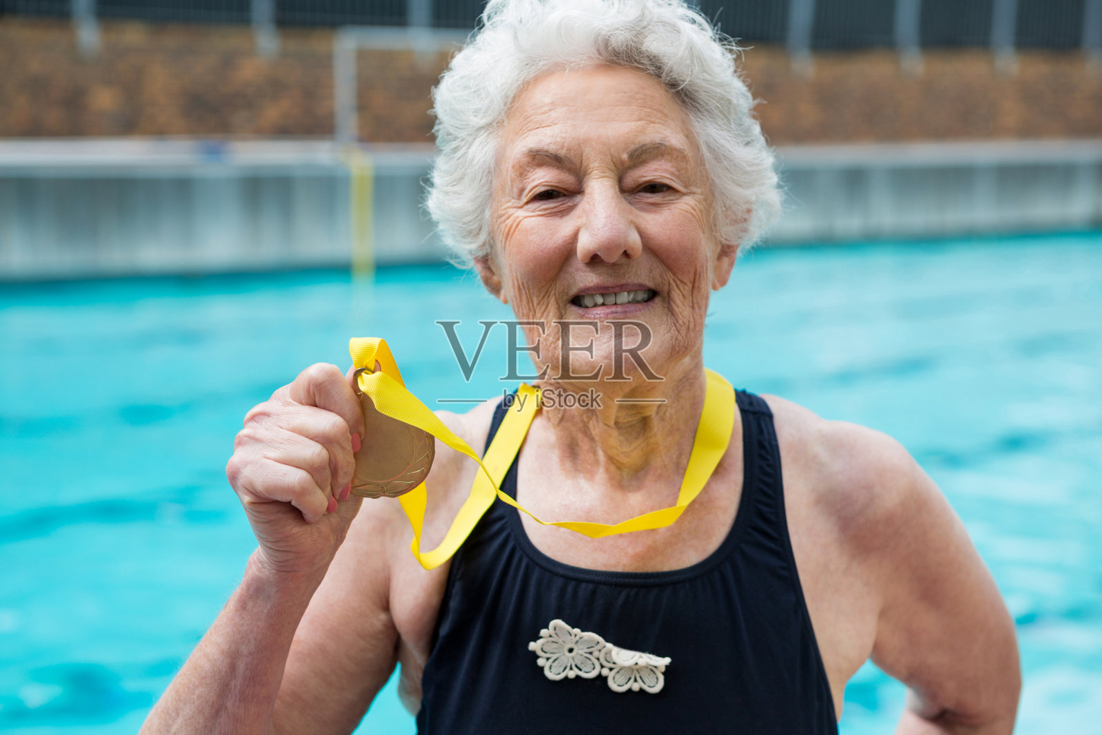 在泳池边展示金牌的资深女子照片摄影图片