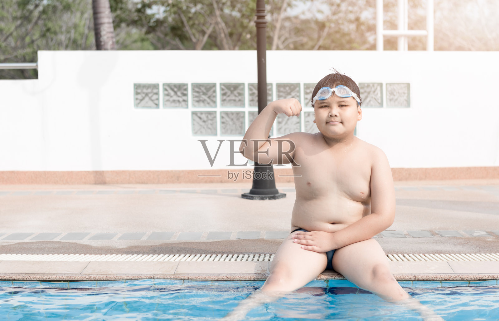 肥胖的胖男孩坐在游泳池上照片摄影图片