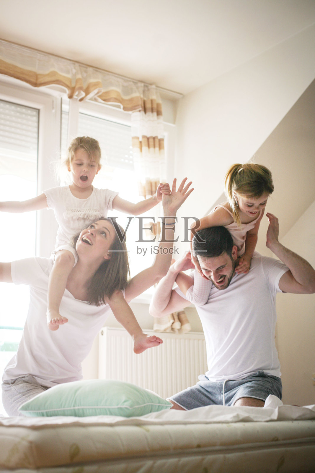 幸福的家庭在床上玩耍。照片摄影图片