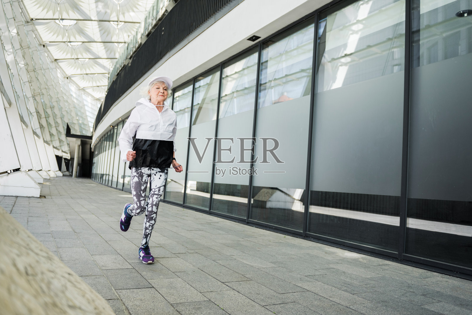 一个非常健康的老妇人沿着现代城市建筑跑步照片摄影图片
