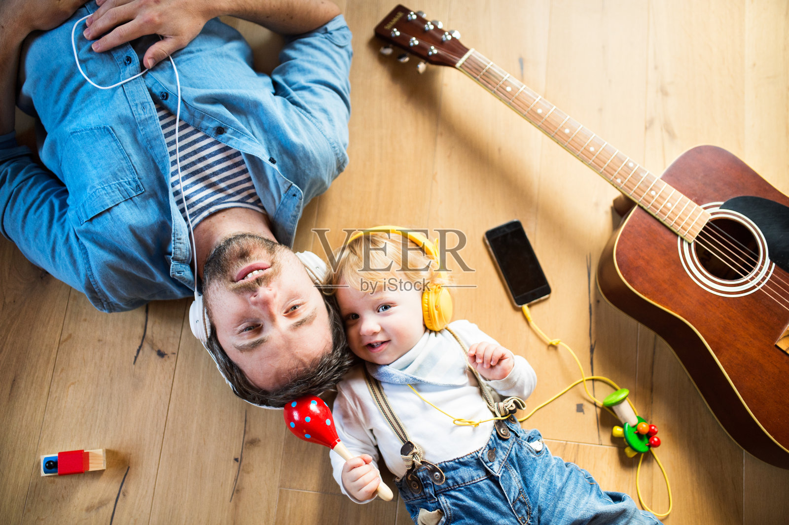 父子俩拿着智能手机和耳机，听着音乐。照片摄影图片