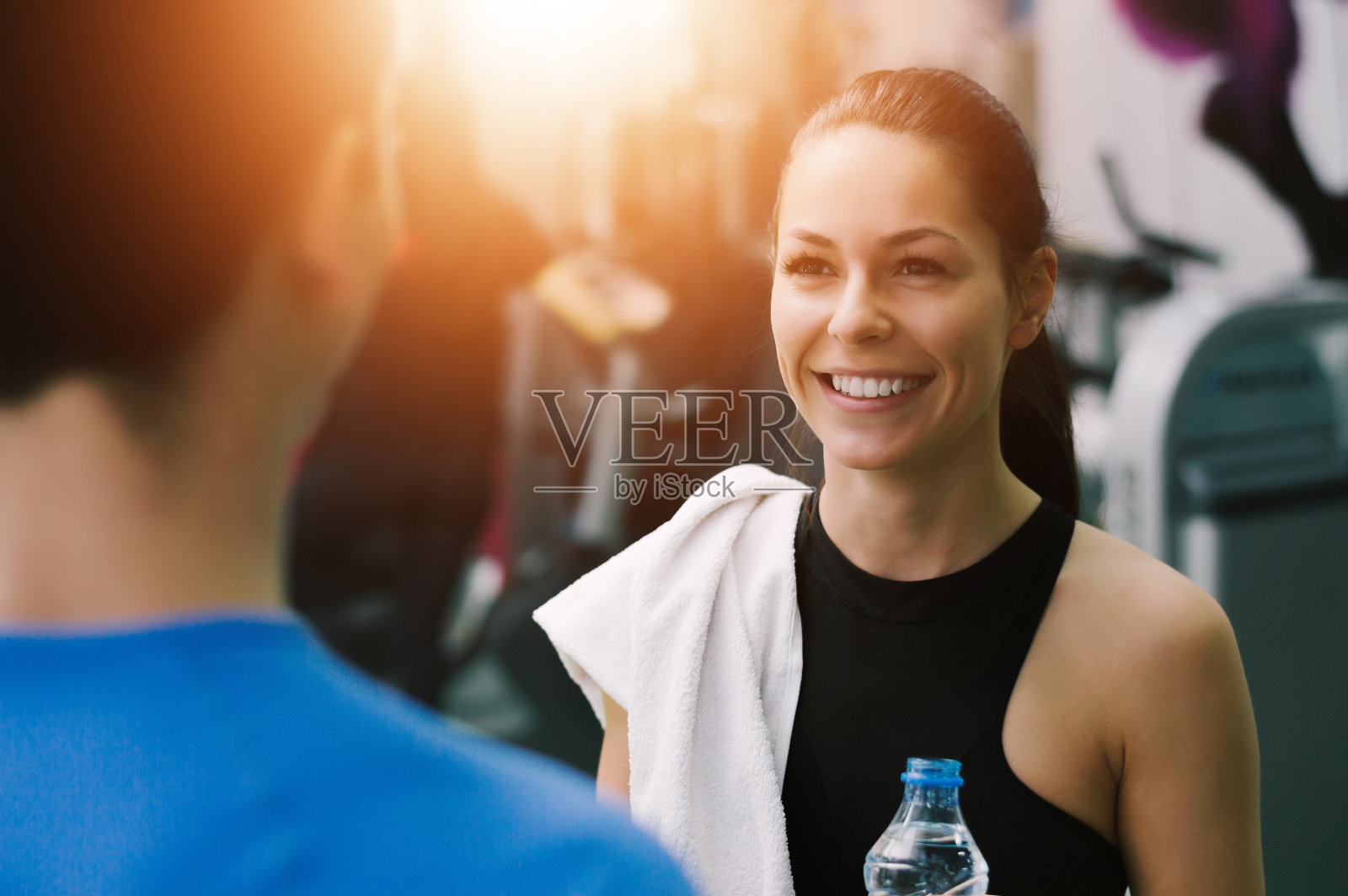 年轻女子在健身房微笑着和她的健身教练交谈照片摄影图片
