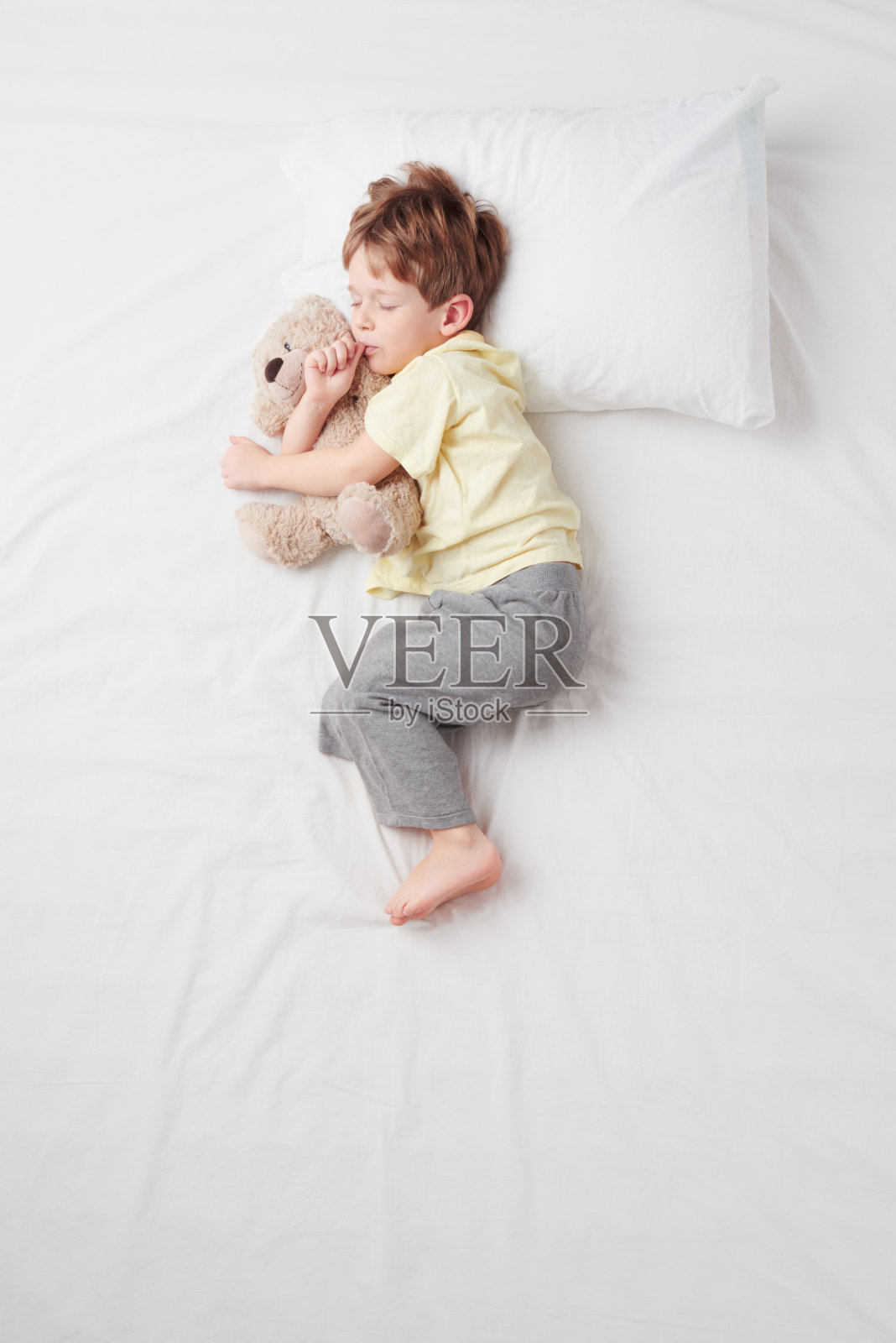 俯视图小男孩睡在胎儿的姿势照片摄影图片