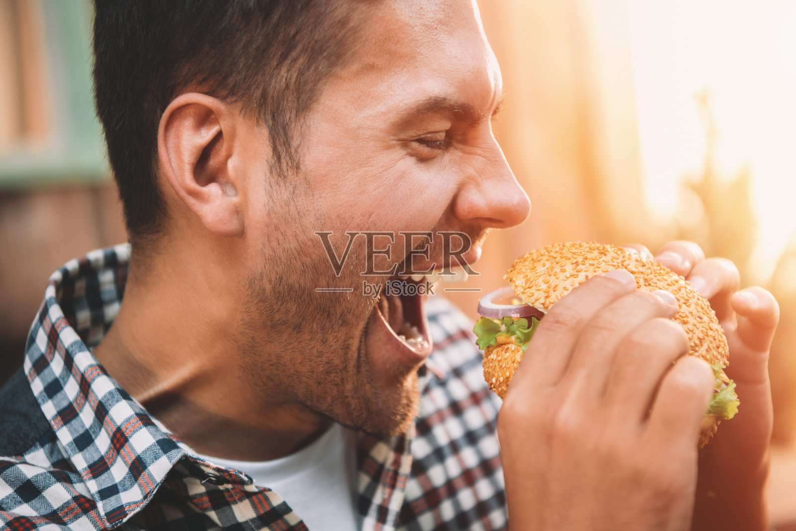 特写侧面的年轻人持有和咬美食自制汉堡包照片摄影图片