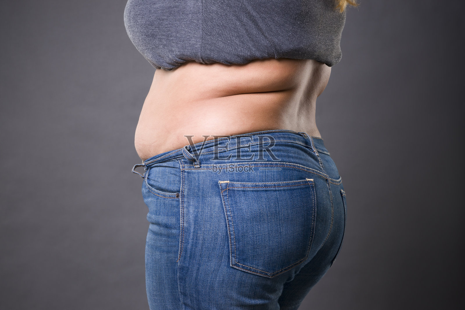 胖肚子的女人穿着蓝色牛仔裤，胖肚子的女人，腹部有妊娠纹特写照片摄影图片