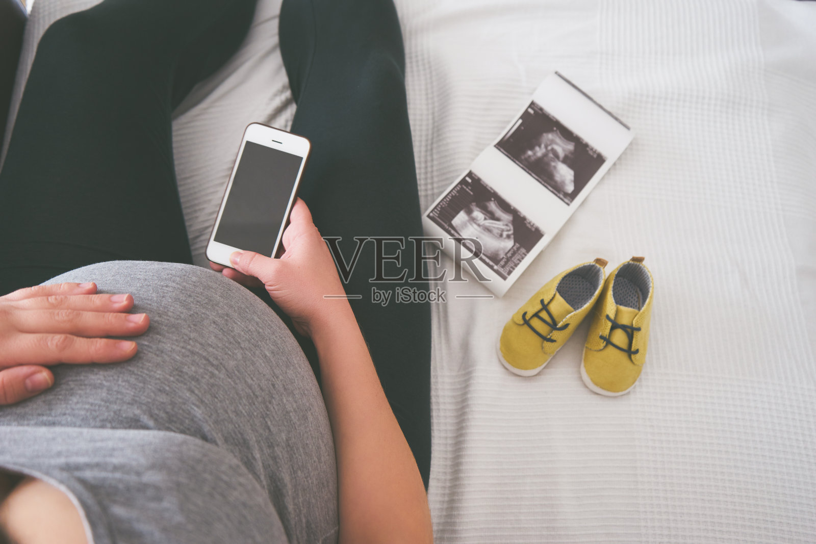 一名年轻孕妇在沙发上玩智能手机照片摄影图片