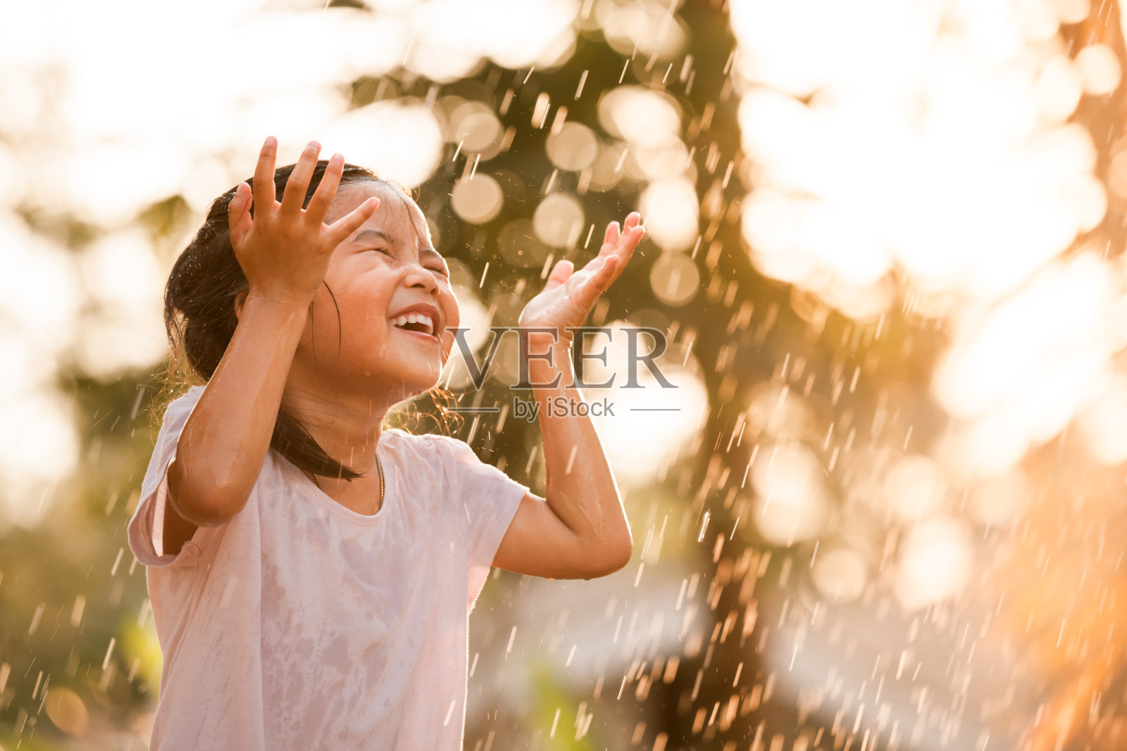 快乐的亚洲小女孩玩雨的乐趣照片摄影图片