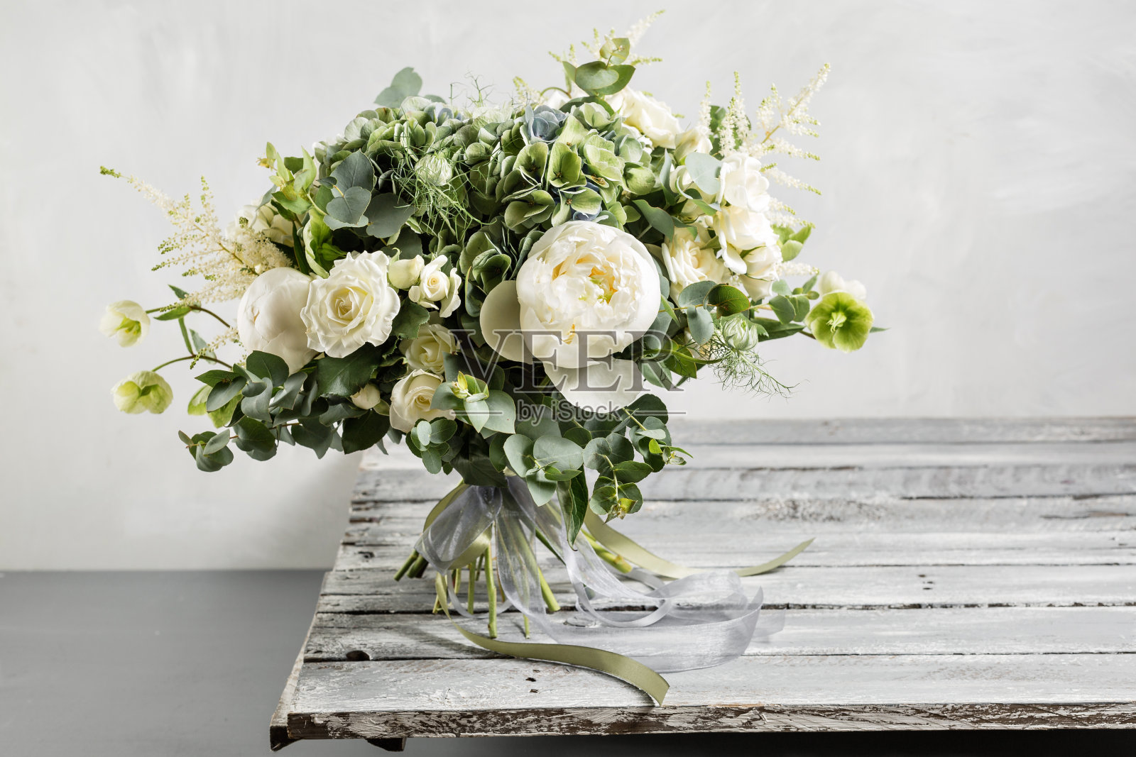 新娘的花束。新娘的。古色古香的木桌上，点缀着美丽的混合鲜花和绿叶，丝带点缀着。复古风格照片摄影图片