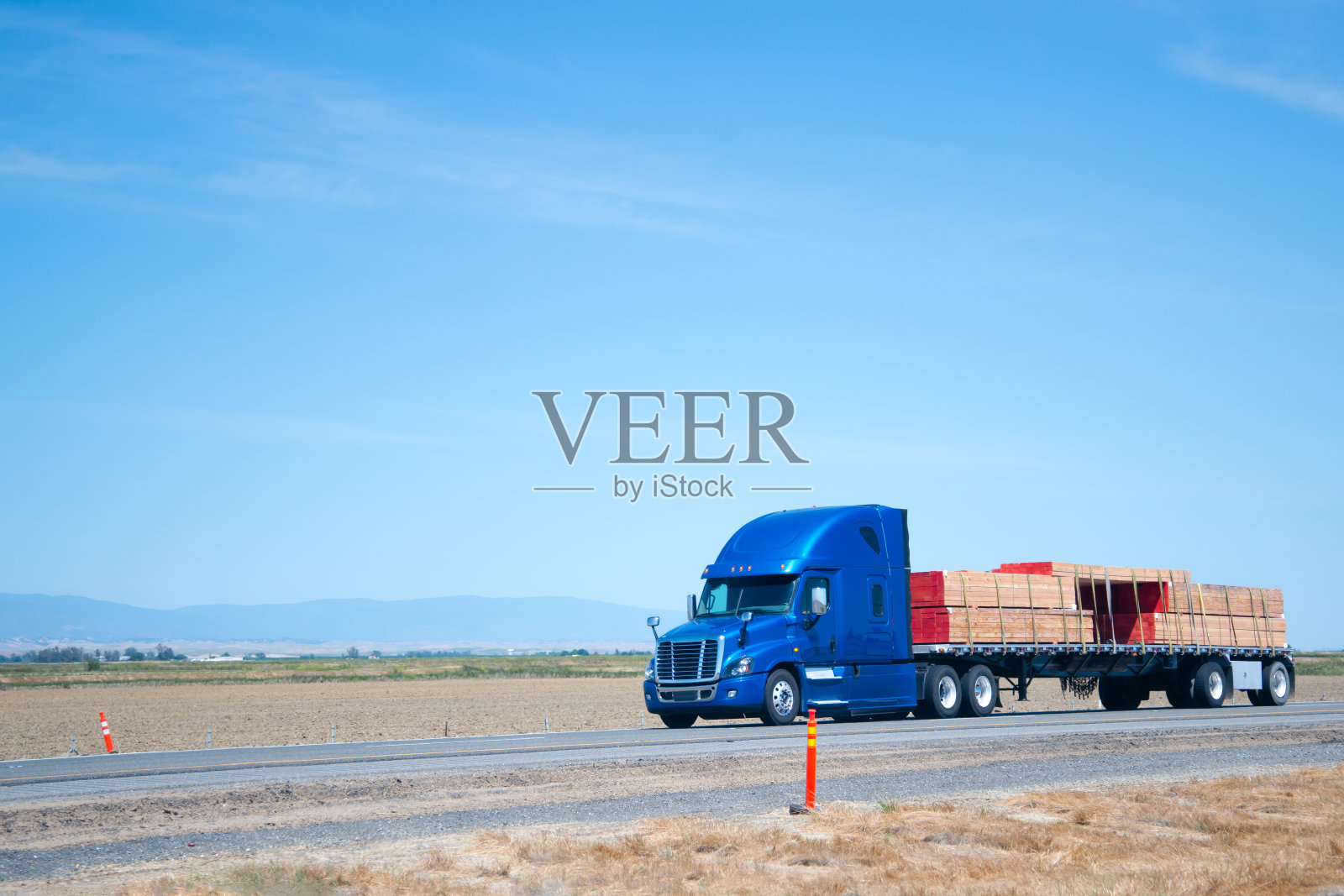 大卡车蓝色半挂车与平床拖车运输木材木材在平坦的道路上照片摄影图片