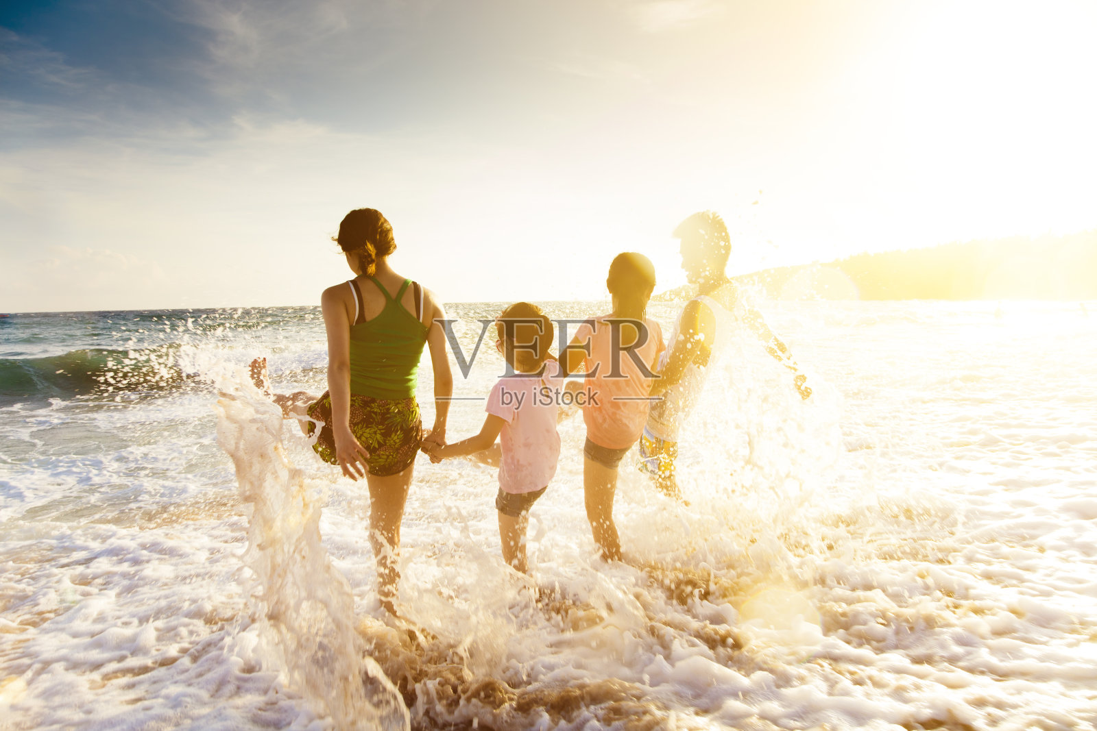 快乐的年轻家庭在海滩上玩日落照片摄影图片