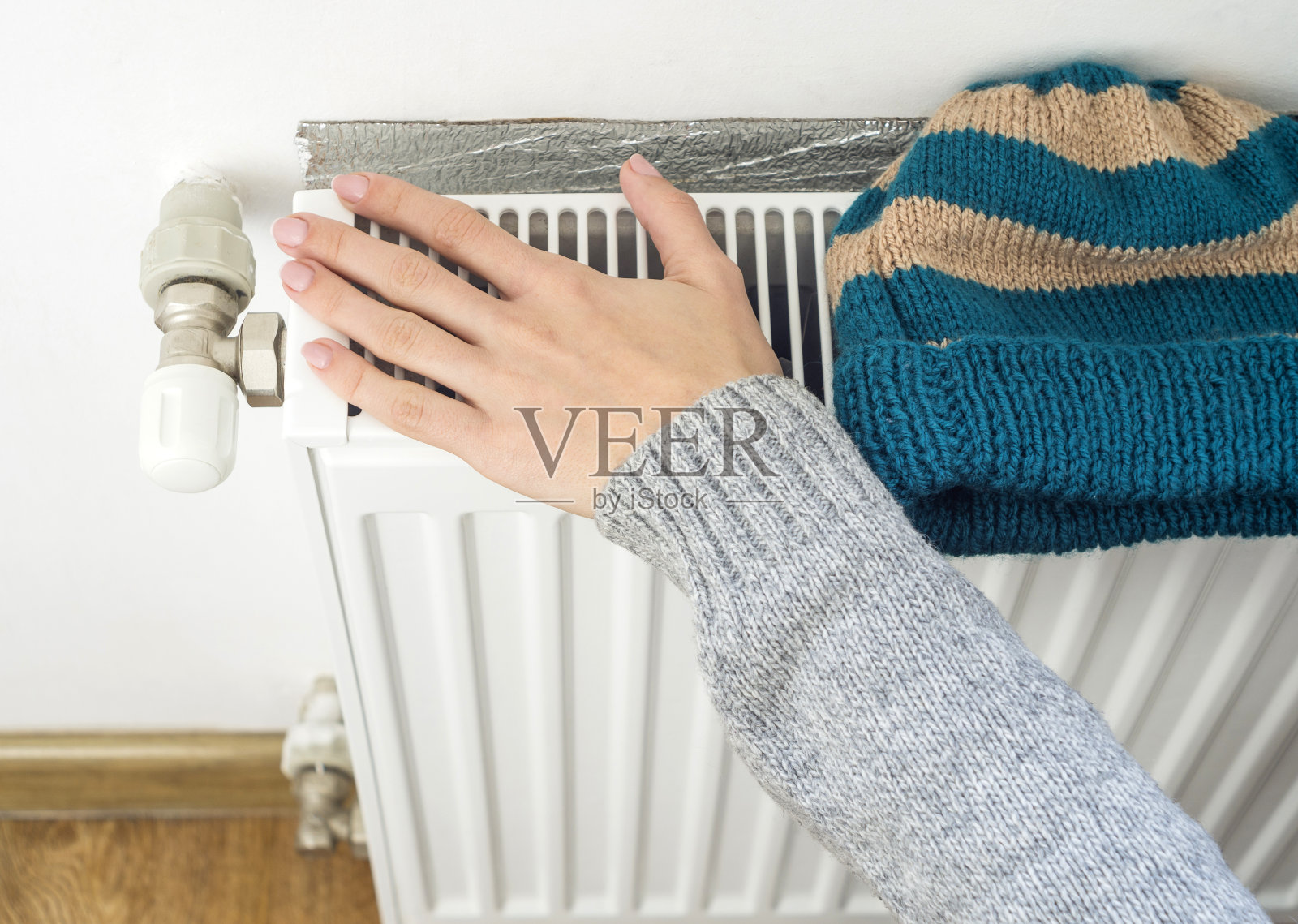 女人的手调节加热器恒温器在冬天的时间照片摄影图片