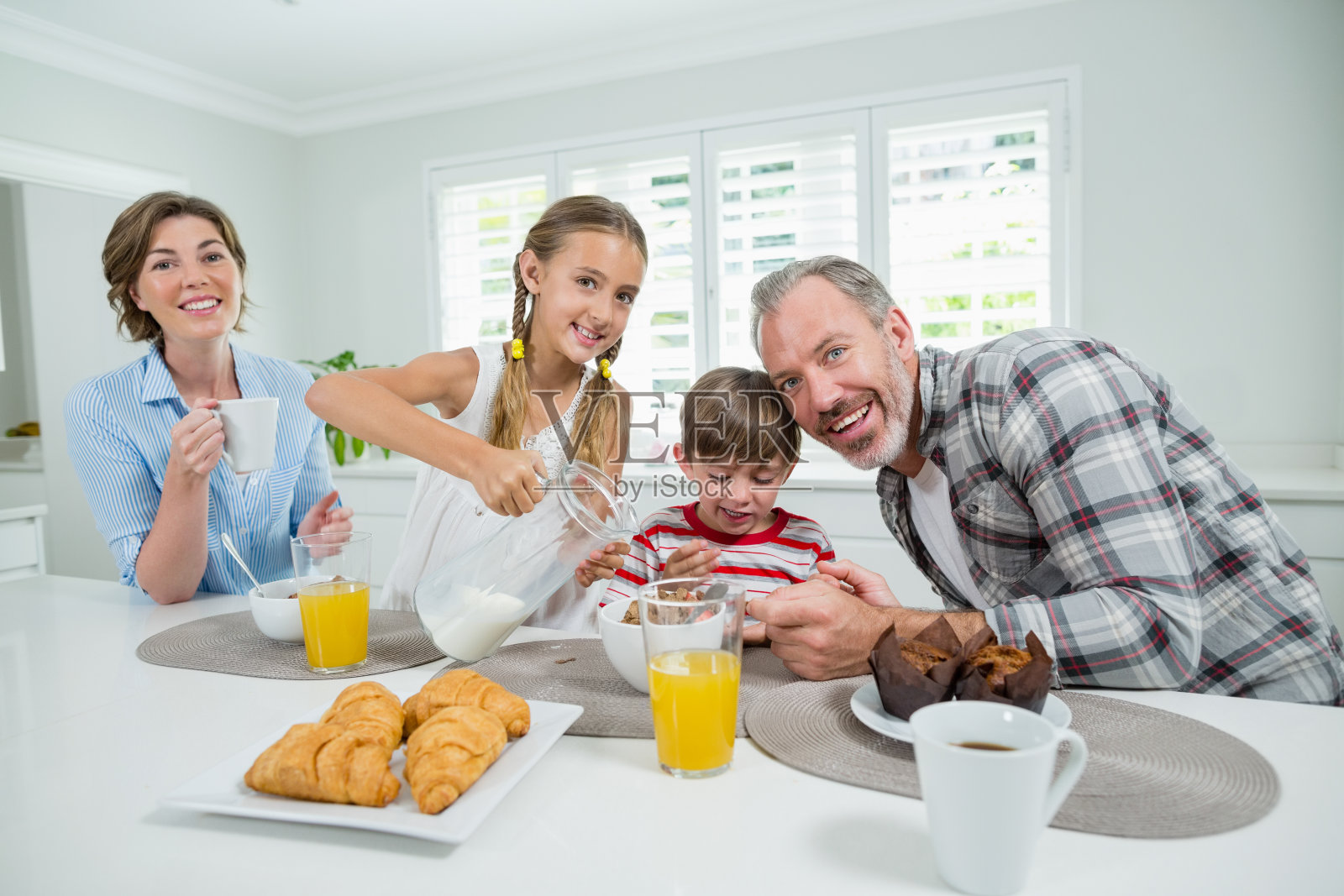一家人微笑着在厨房吃早餐照片摄影图片