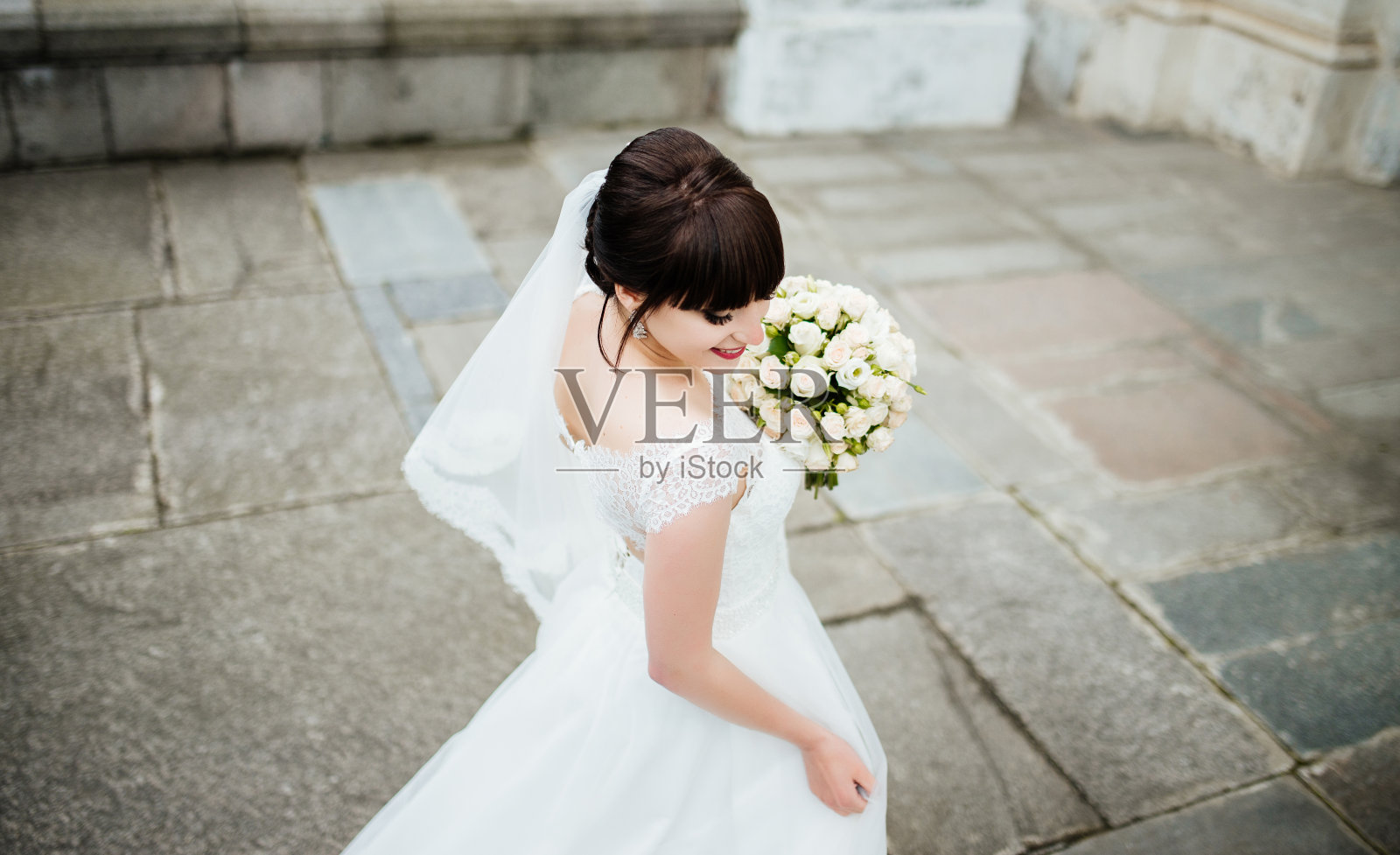 新娘捧着一束鲜花，转过身微笑着。婚礼肖像美丽的新娘。的婚礼。结婚的那一天。照片摄影图片