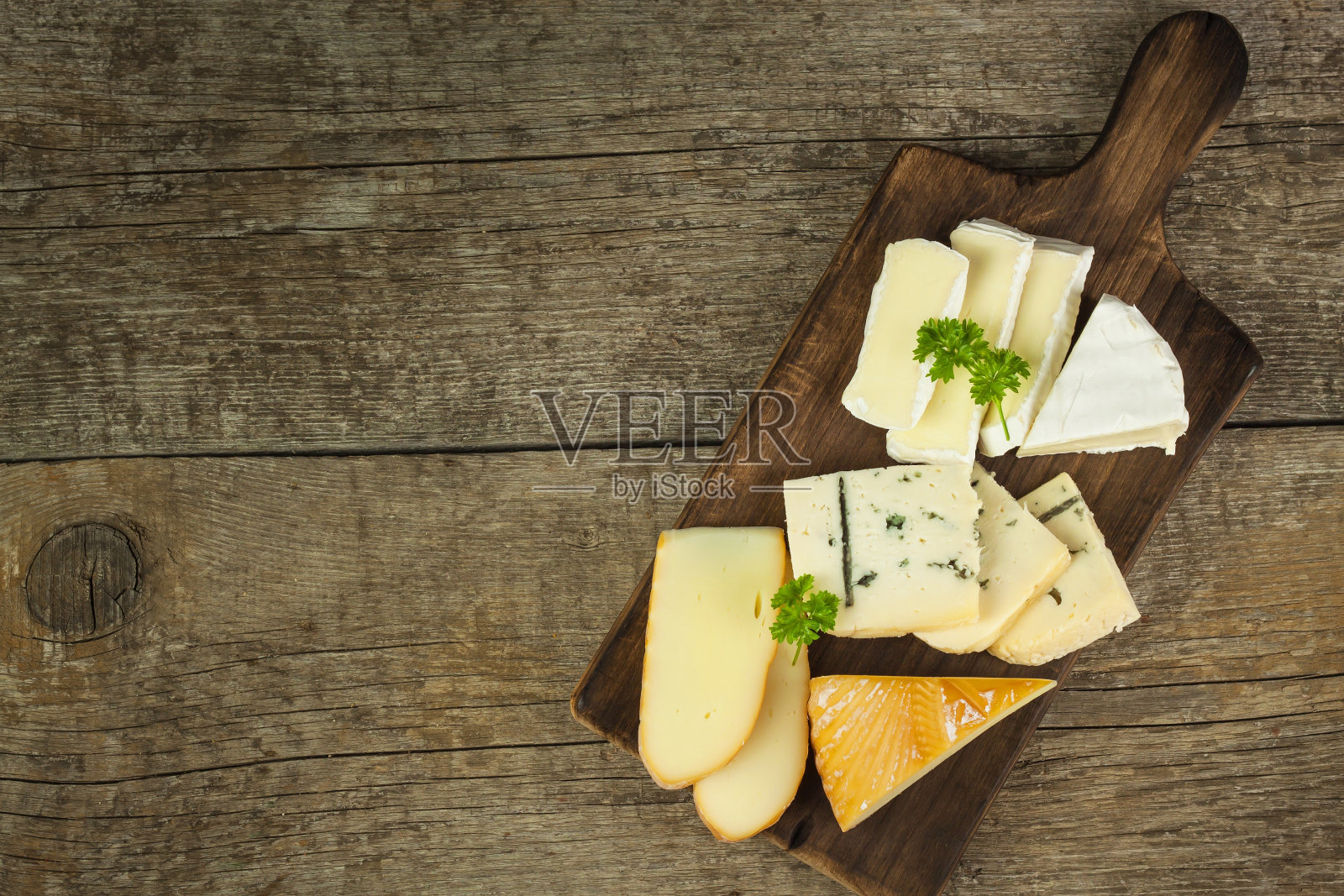 在木头砧板上放不同种类的奶酪。照片摄影图片