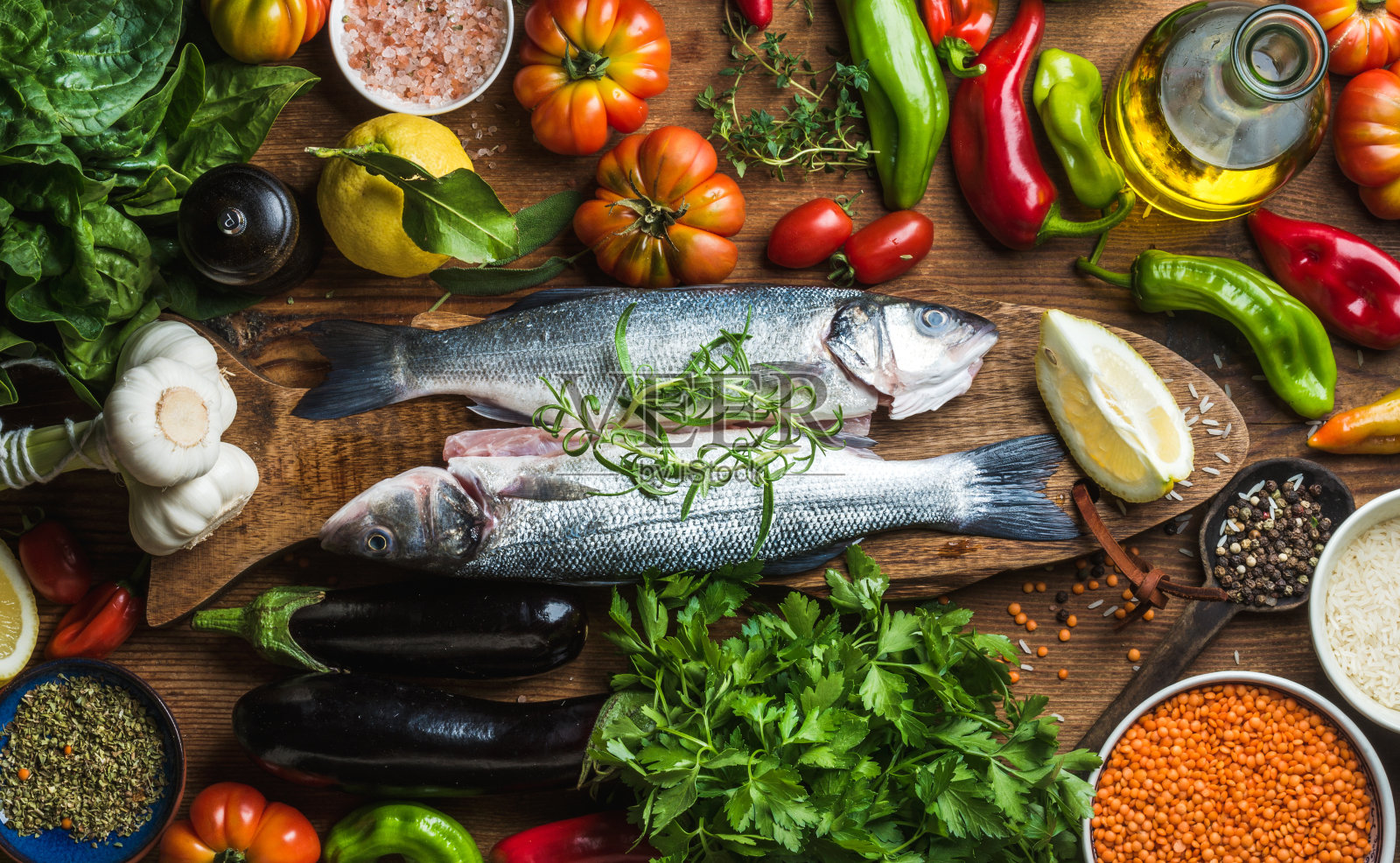 生的未经烹煮的鲈鱼，配以蔬菜、谷物、香草和香料照片摄影图片