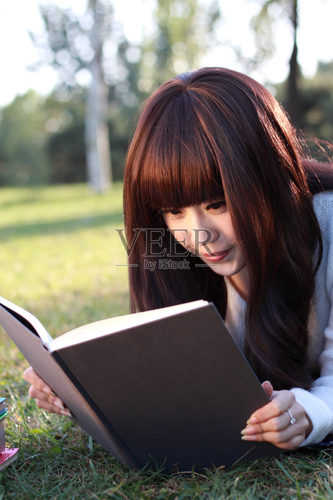 研究快乐的年轻女子读她的书。照片摄影图片