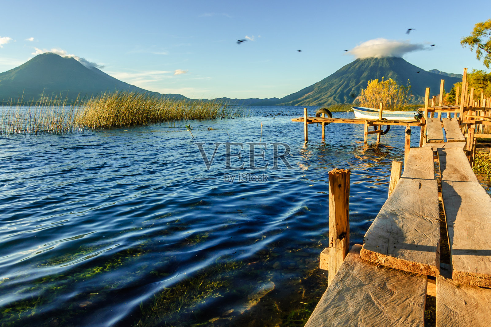 清晨的阳光照在危地马拉阿提兰湖的三座火山上照片摄影图片