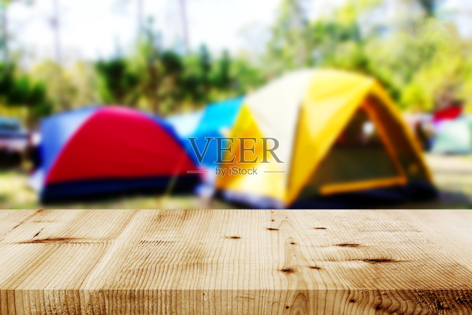森林里的木头桌子和模糊的露营和帐篷。照片摄影图片