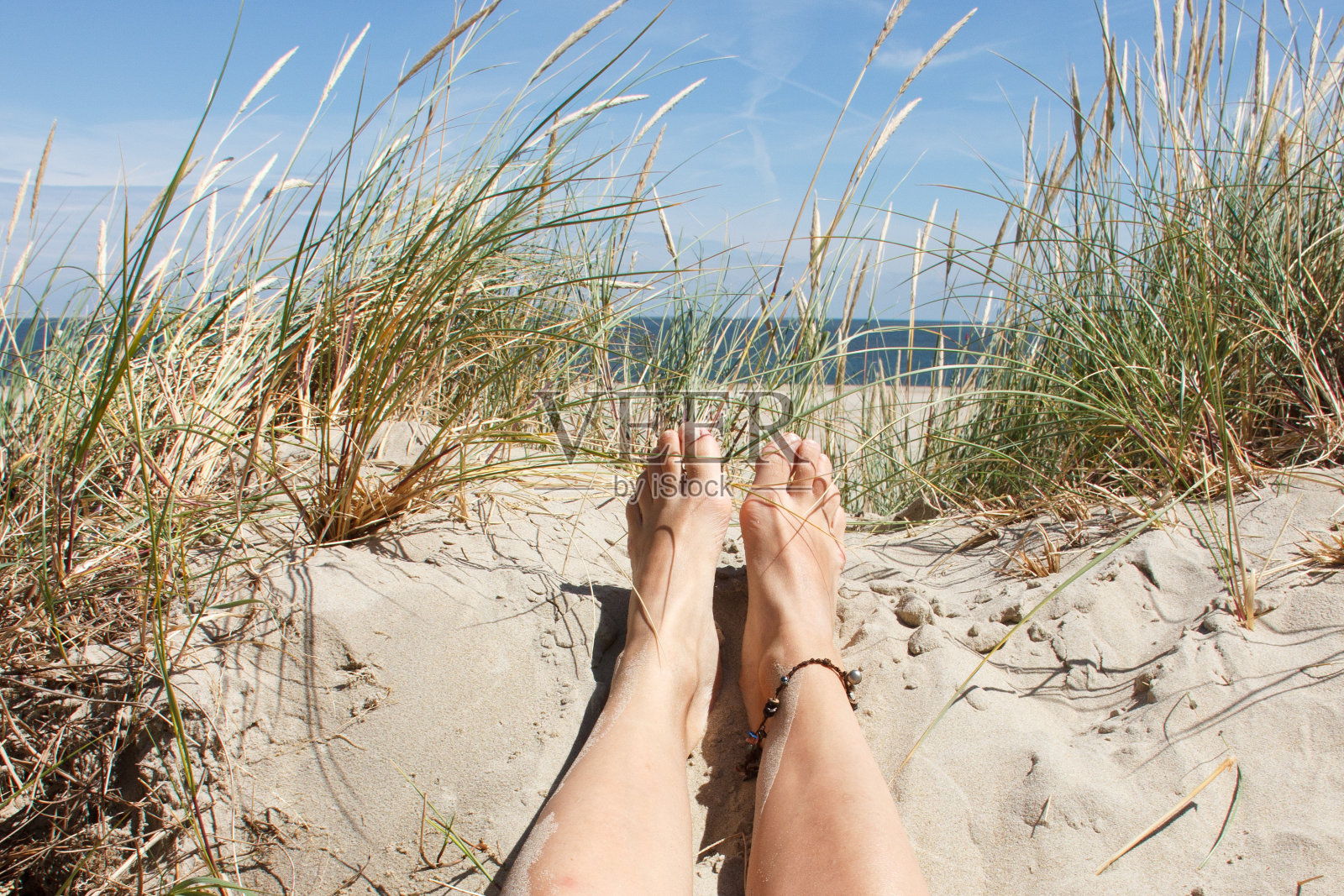 阳光明媚的海滩，女人的脚在沙滩上照片摄影图片