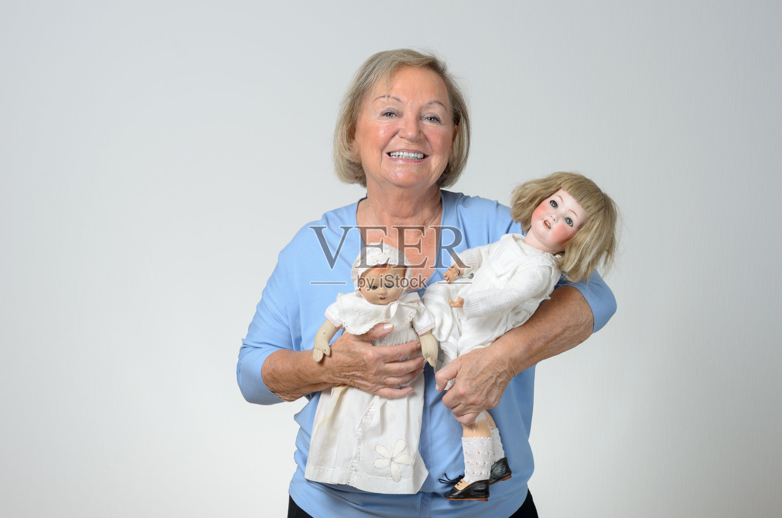 老妇人拿着两个古董娃娃照片摄影图片