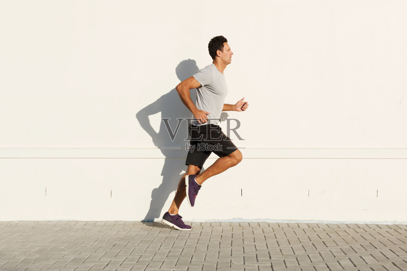 中年男子在白墙边奔跑照片摄影图片