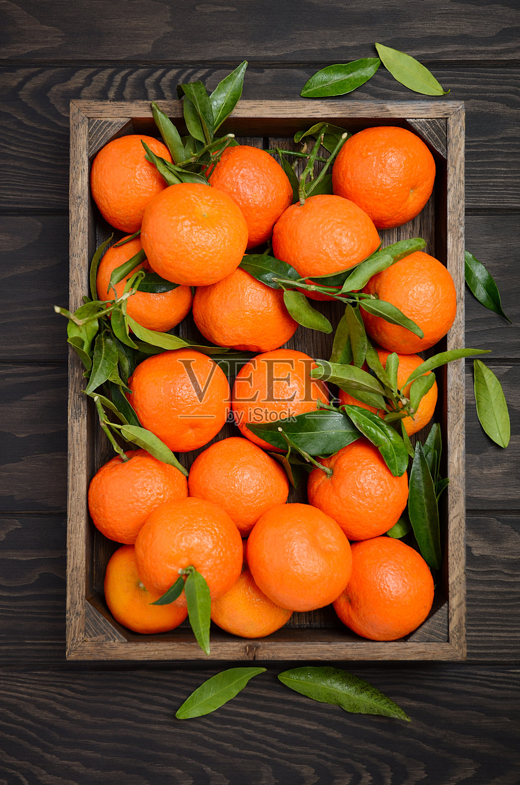 新鲜的柑橘类小柑橘，叶子在深色木质背景上照片摄影图片