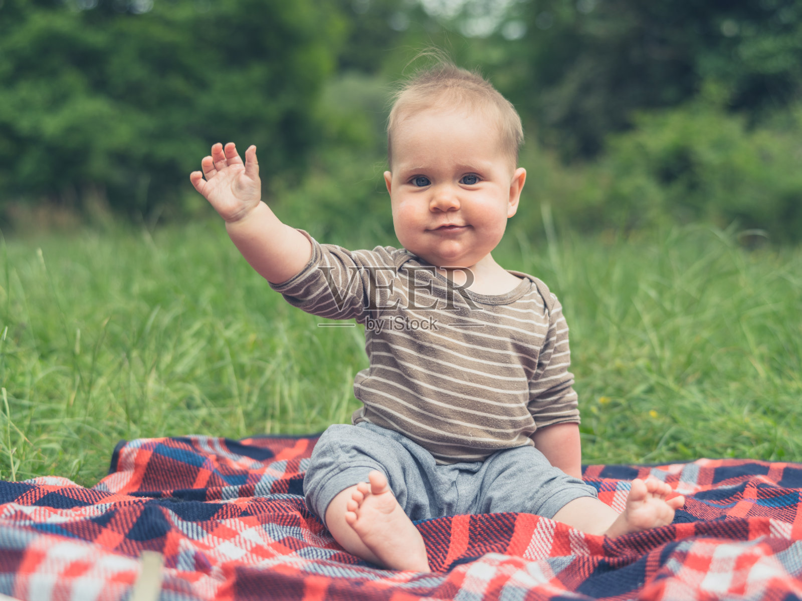 可爱的小宝贝在大自然的野餐毯上挥手照片摄影图片