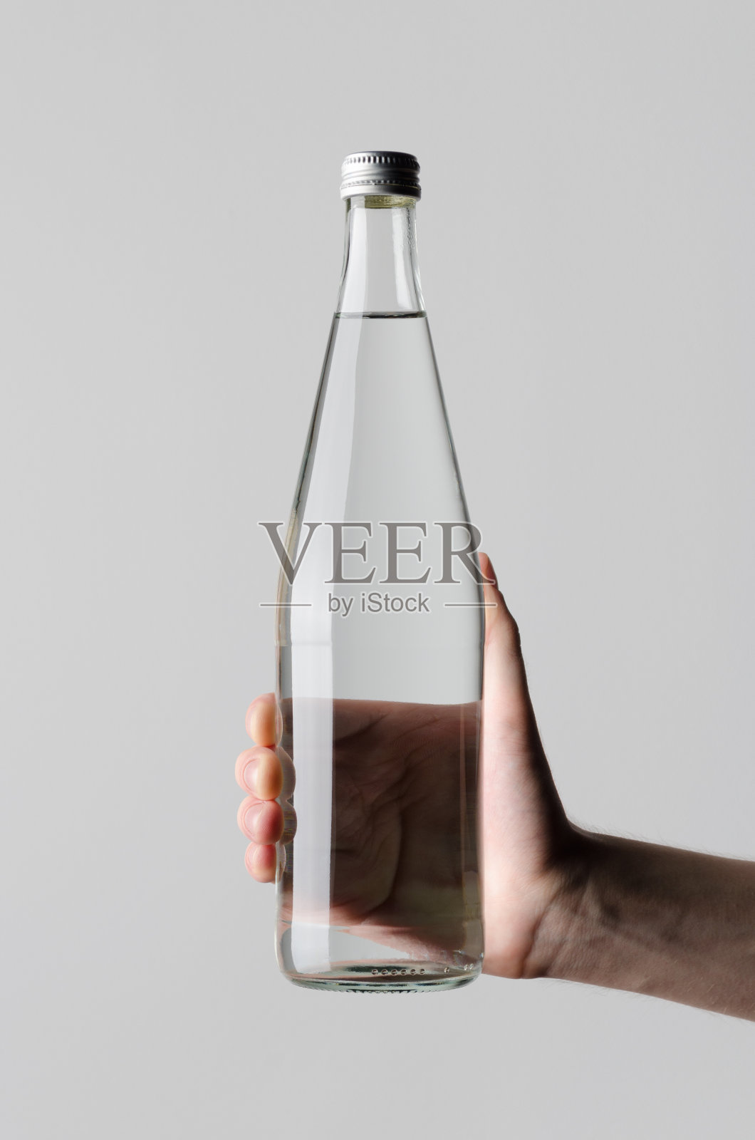 水瓶模型-在灰色的背景下，男性的手拿着一个水瓶照片摄影图片
