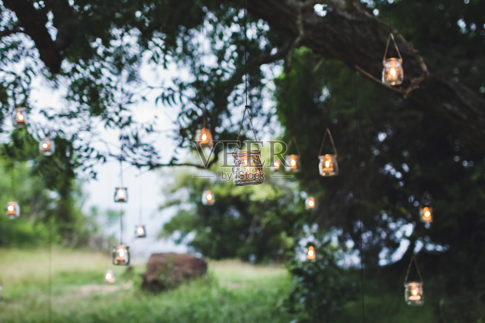晚上的婚礼仪式用许多复古的灯和蜡烛在大树上照片摄影图片