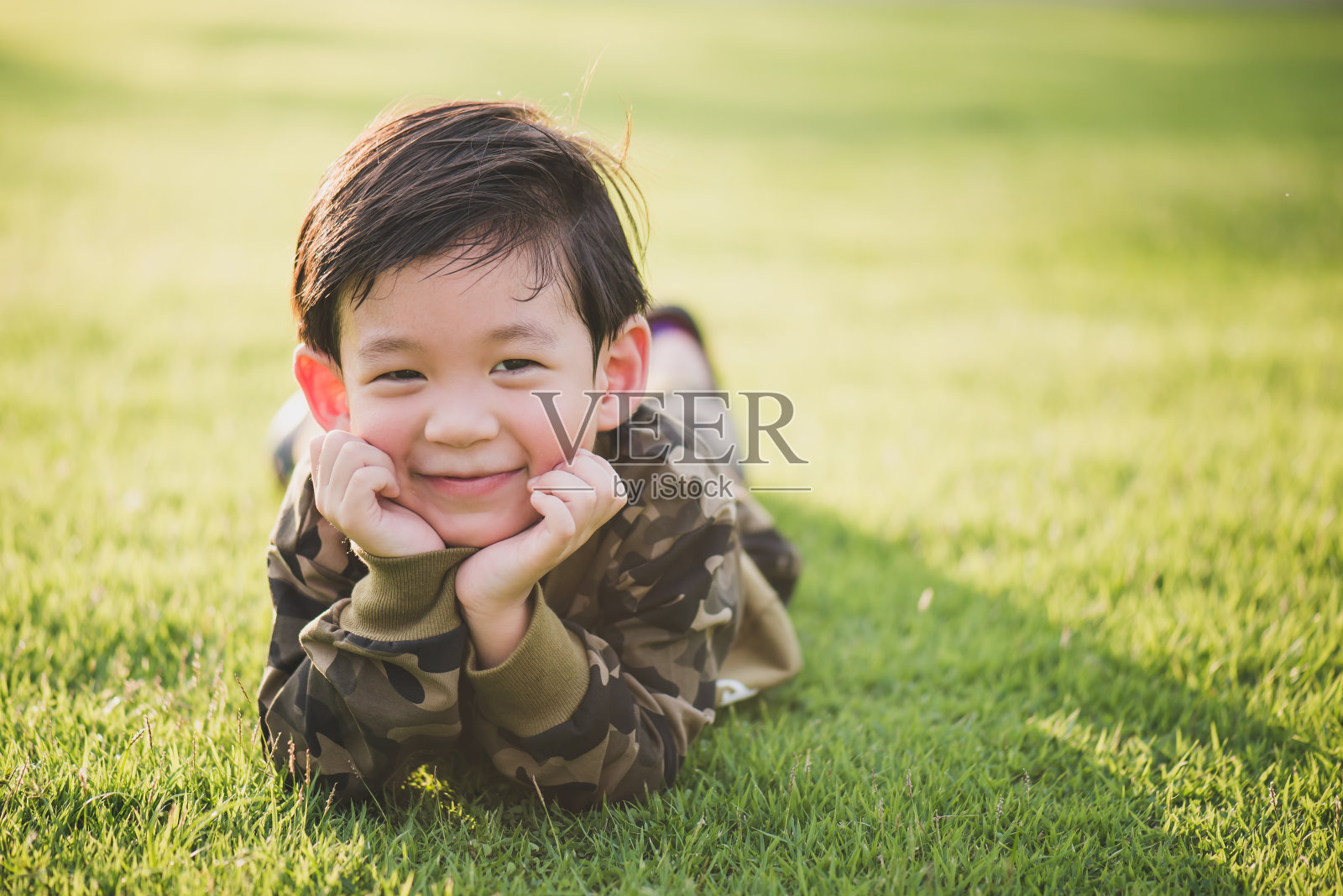 可爱的亚洲孩子躺在绿色的草地上照片摄影图片