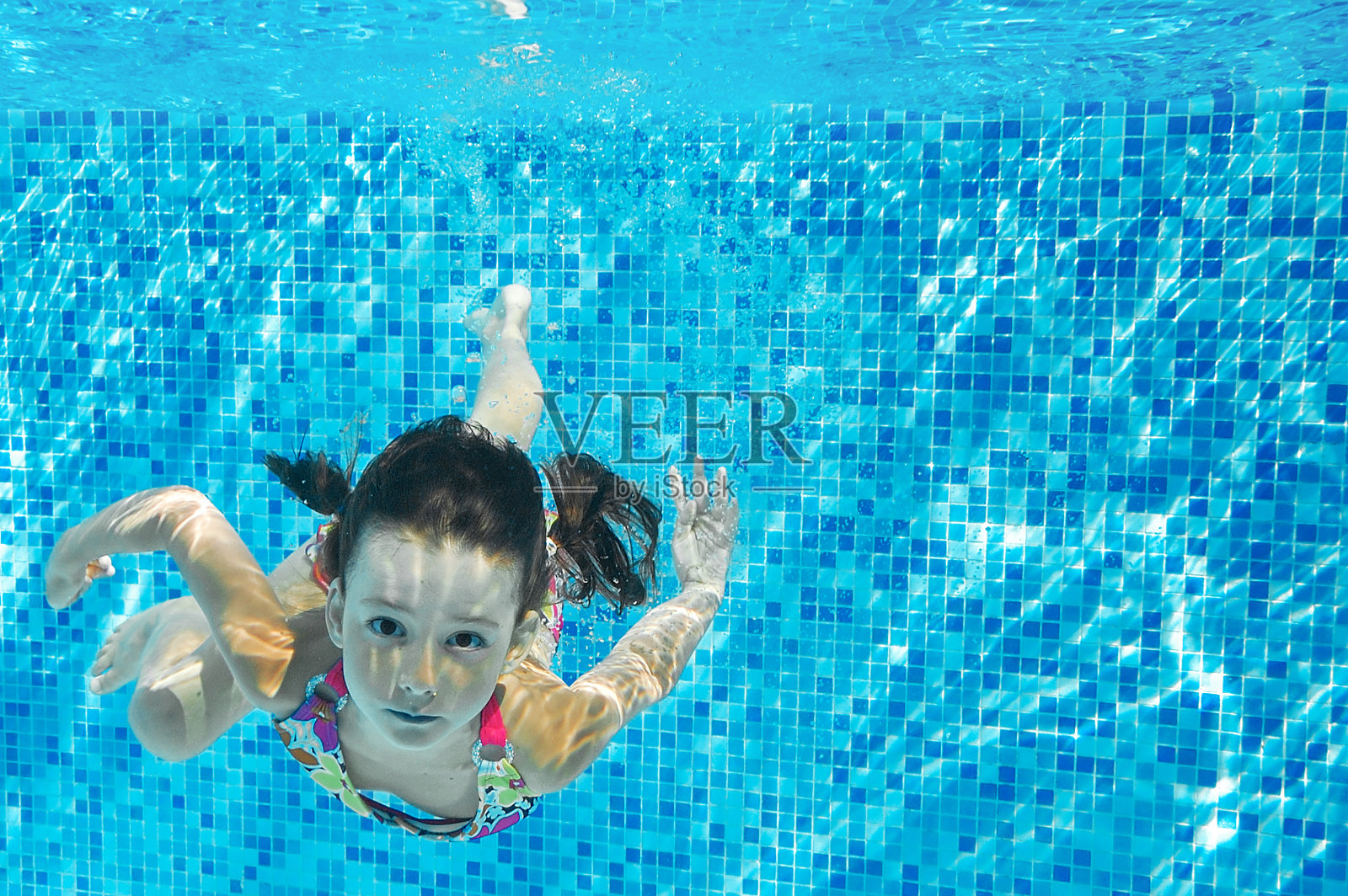 孩子游泳在游泳池水下，快乐活跃的女孩潜水和有乐趣的水下，孩子健身和运动在家庭度假照片摄影图片