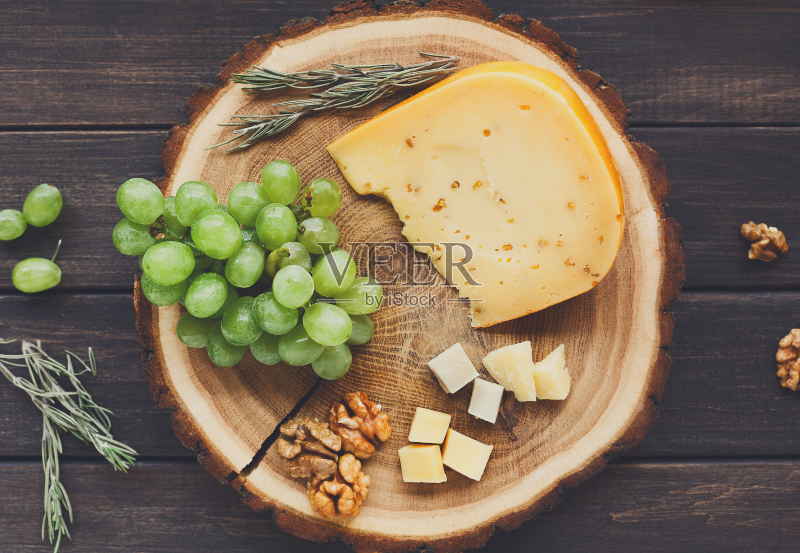 奶酪拼盘，豪达香草配葡萄和天然木盘照片摄影图片