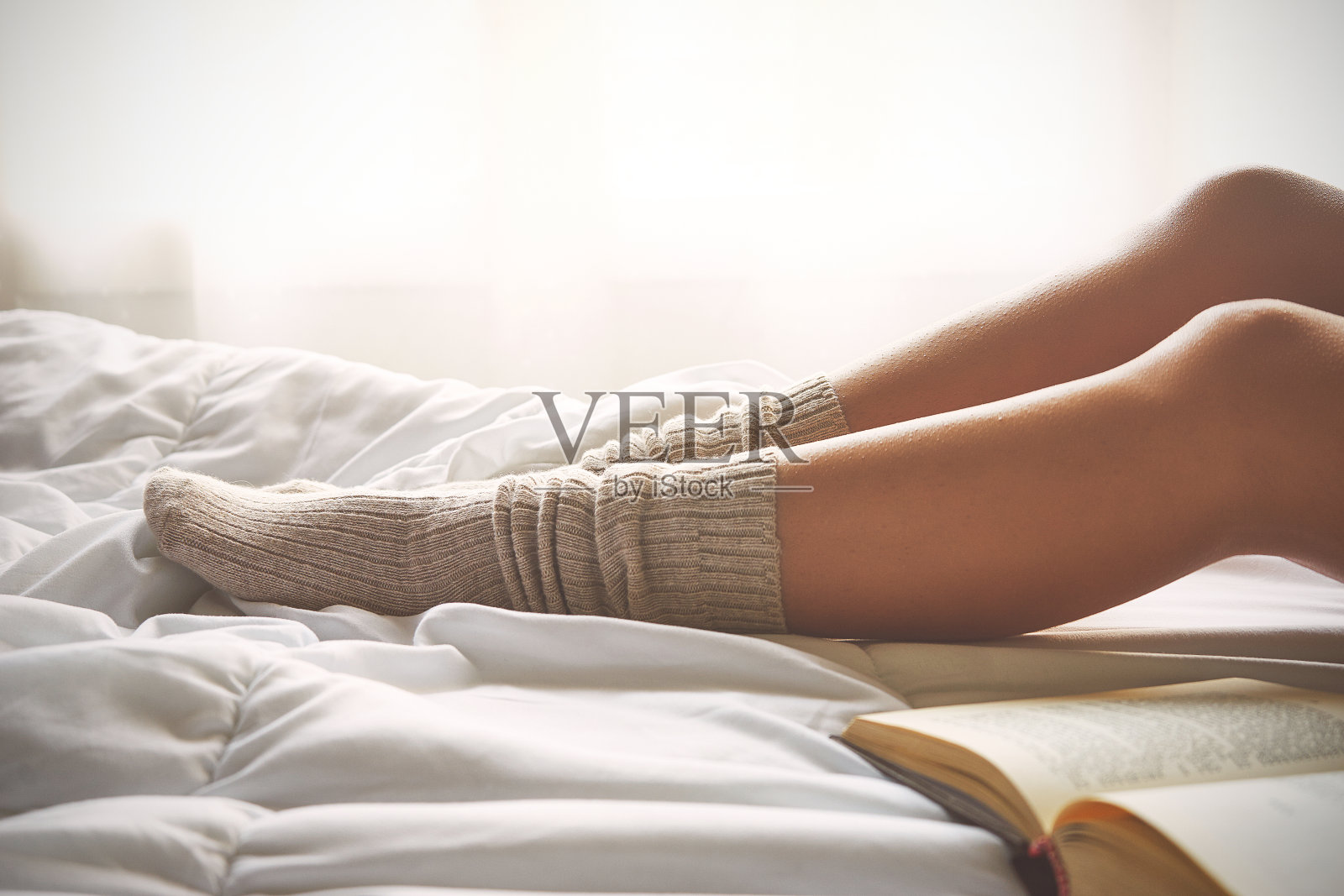 柔软的照片，女人的腿在床上与旧书旁边照片摄影图片